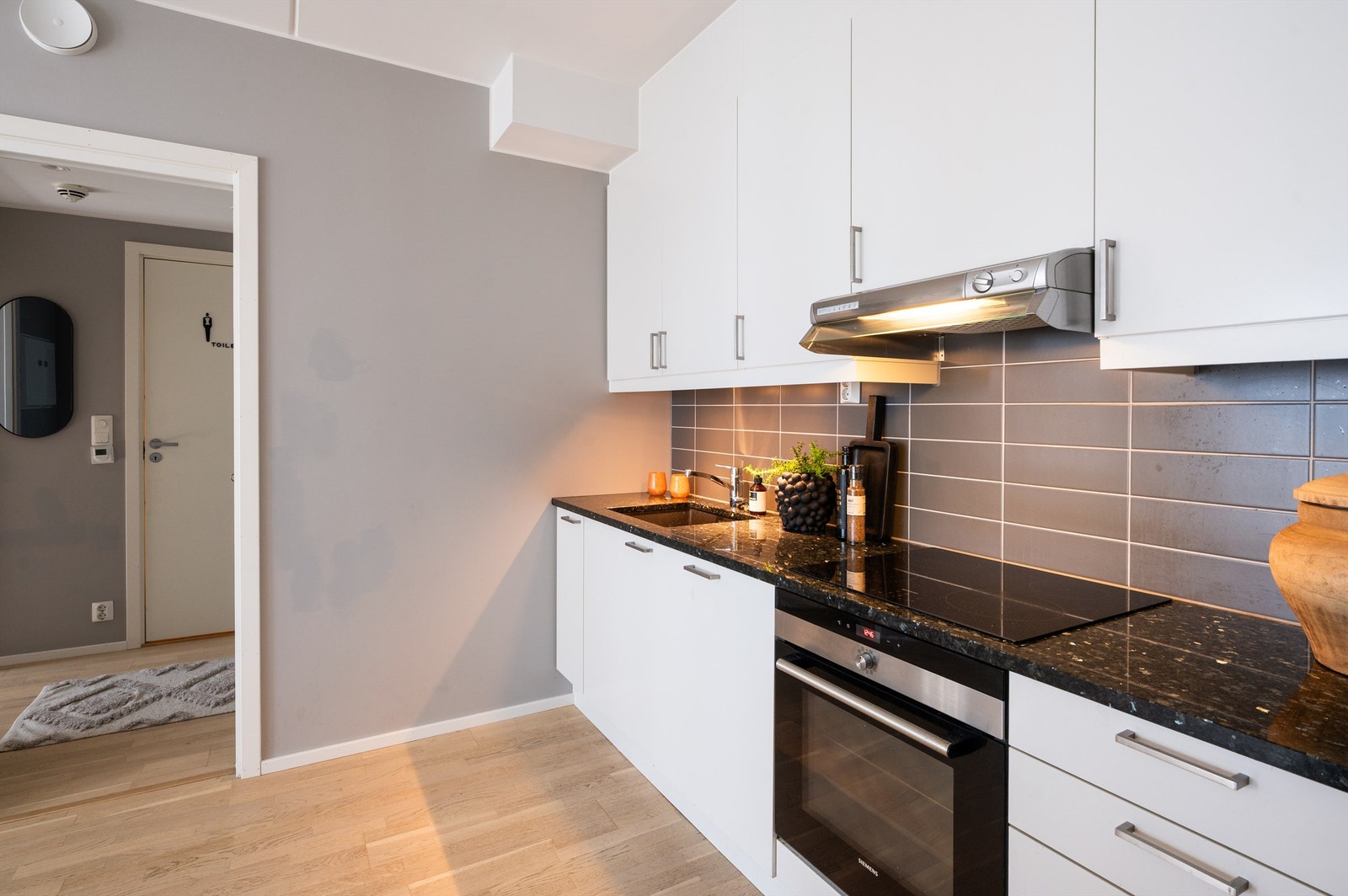 Lekkert kjøkken fra byggeår med hvitevarer som oppvaskmaskin, induksjonstopp og stekeovn sømløst integrert i innredningen Galleribilde