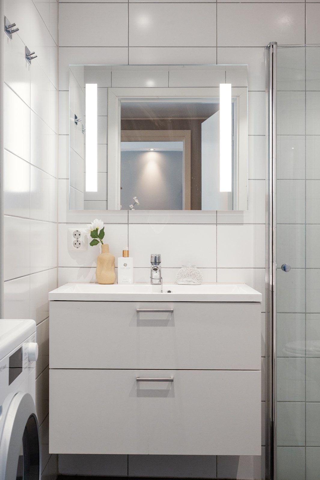 Videre har badet dusjhjørne med innfellbare glassdører og vegghengt klosett. Det er opplegg for vaskemaskin. Galleribilde