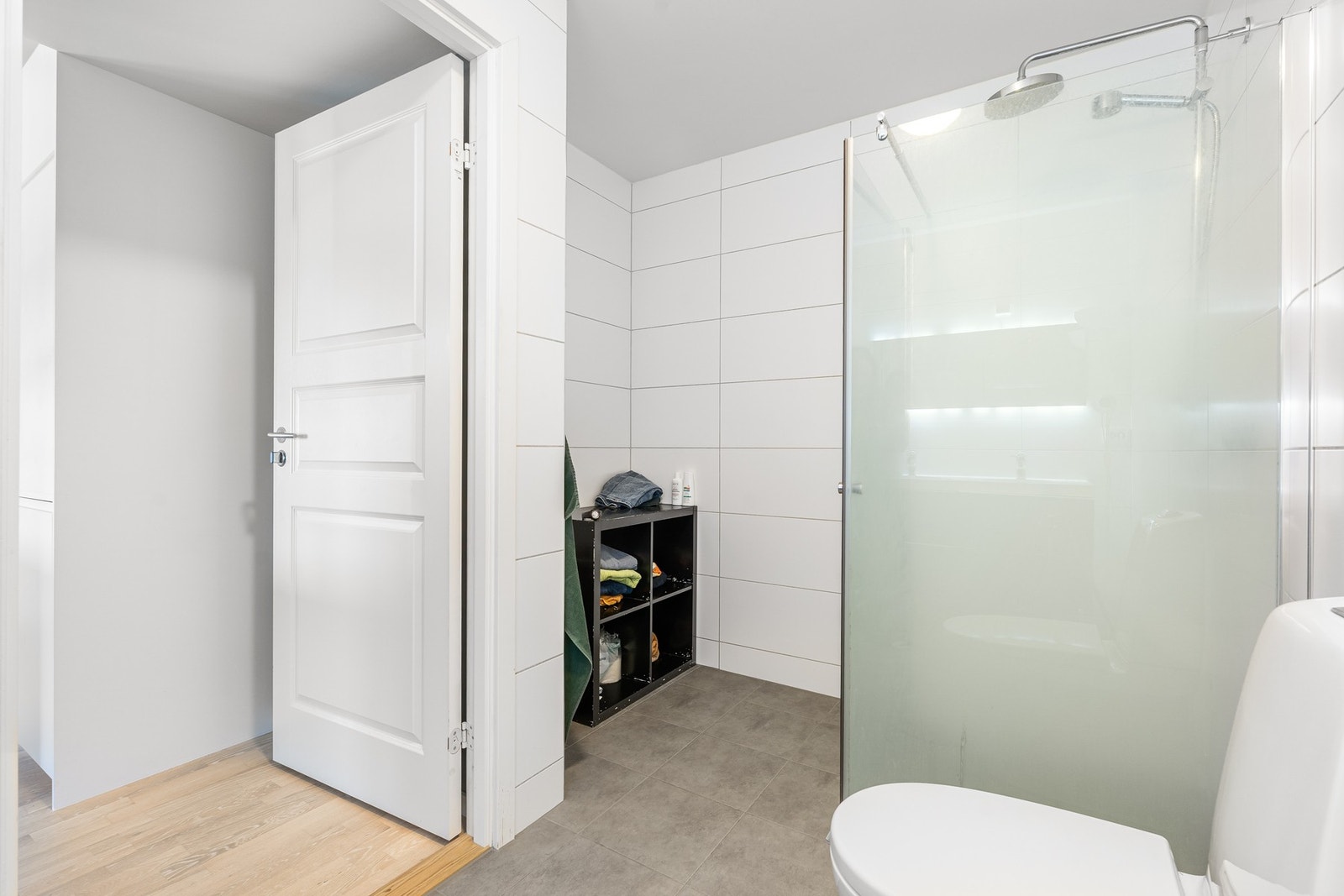 Badet er innredet med dusjhjørne med 2 stk. glassdører og dusjgarnityr montert på vegg. Gulvmontert WC. Galleribilde