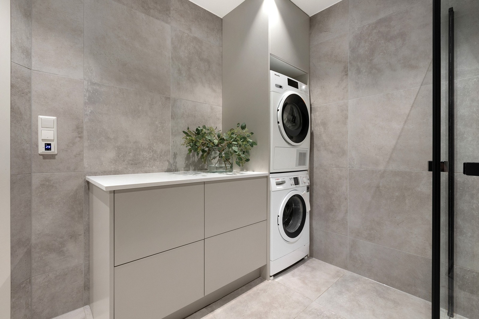 Badet har også praktisk opplegg for vaskemaskin og tørketrommel, plassert i en egen nisje med integrert benk og oppbevaringsskap Galleribilde