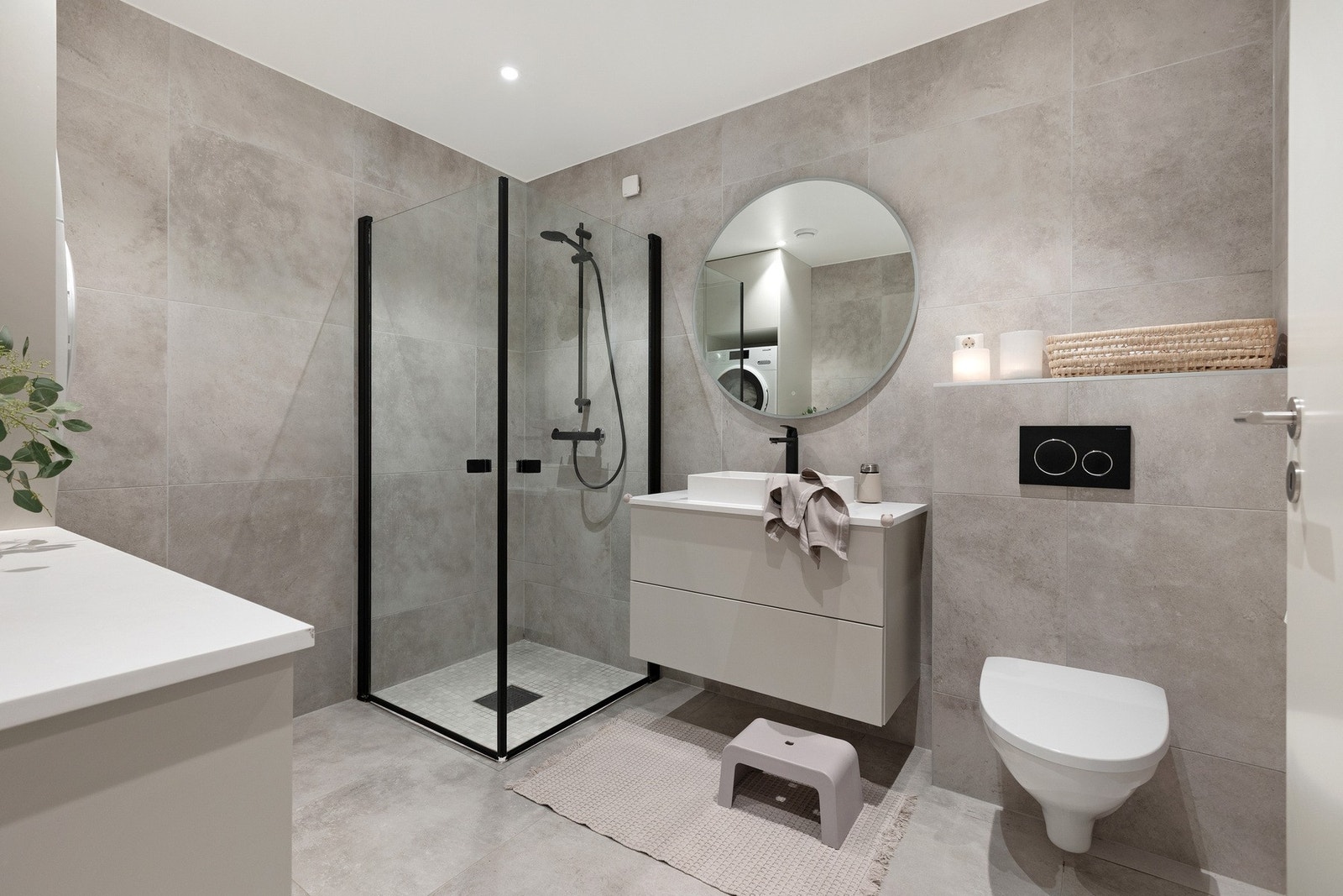 Badet fremstår moderne og stilrent med store lyse fliser på både gulv og vegger, kombinert med et hvitmalt tak. Galleribilde