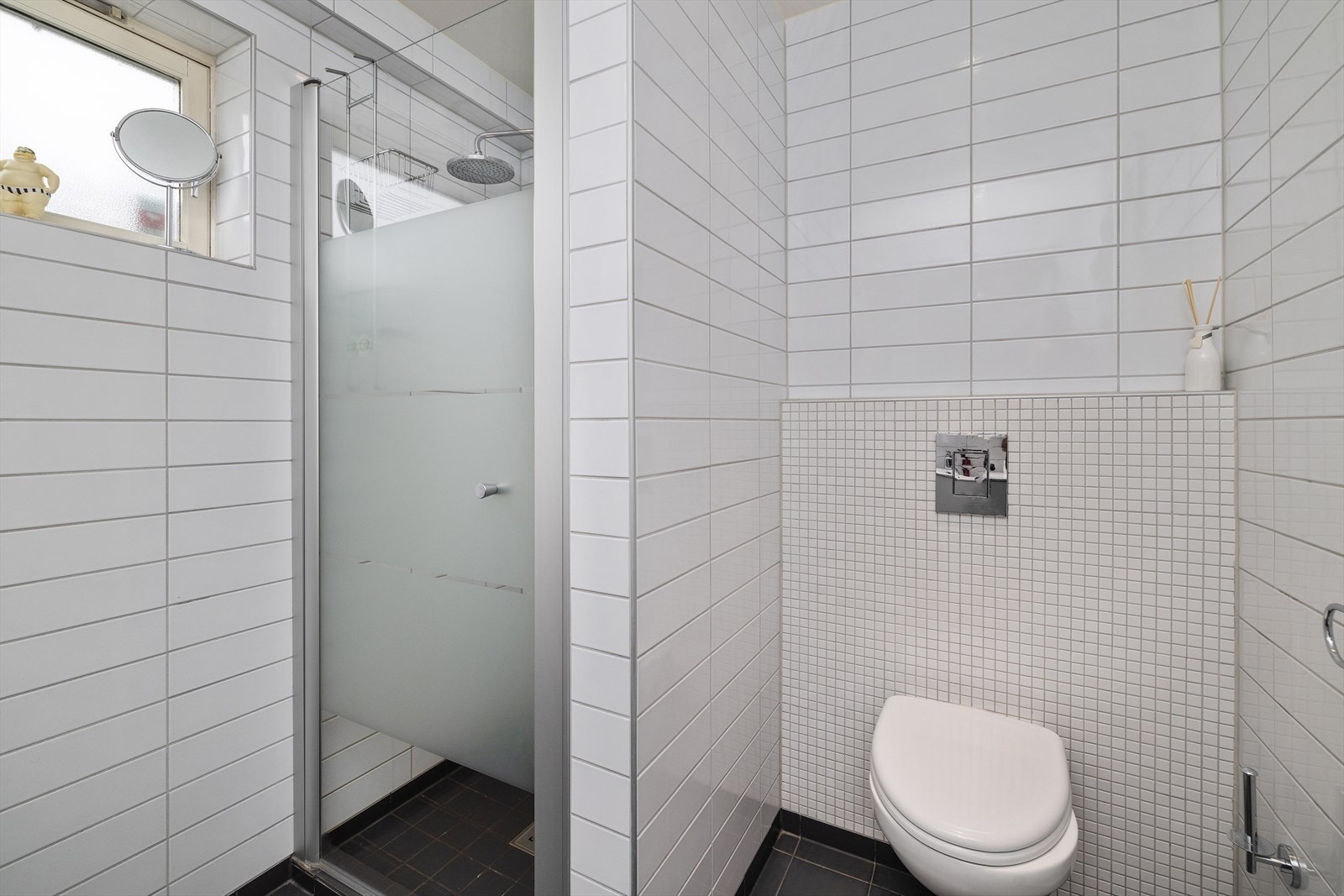 Rommets innredning består av veggmontert toalett, dusjhjørne med glassvegger og en innredning med servant. Galleribilde