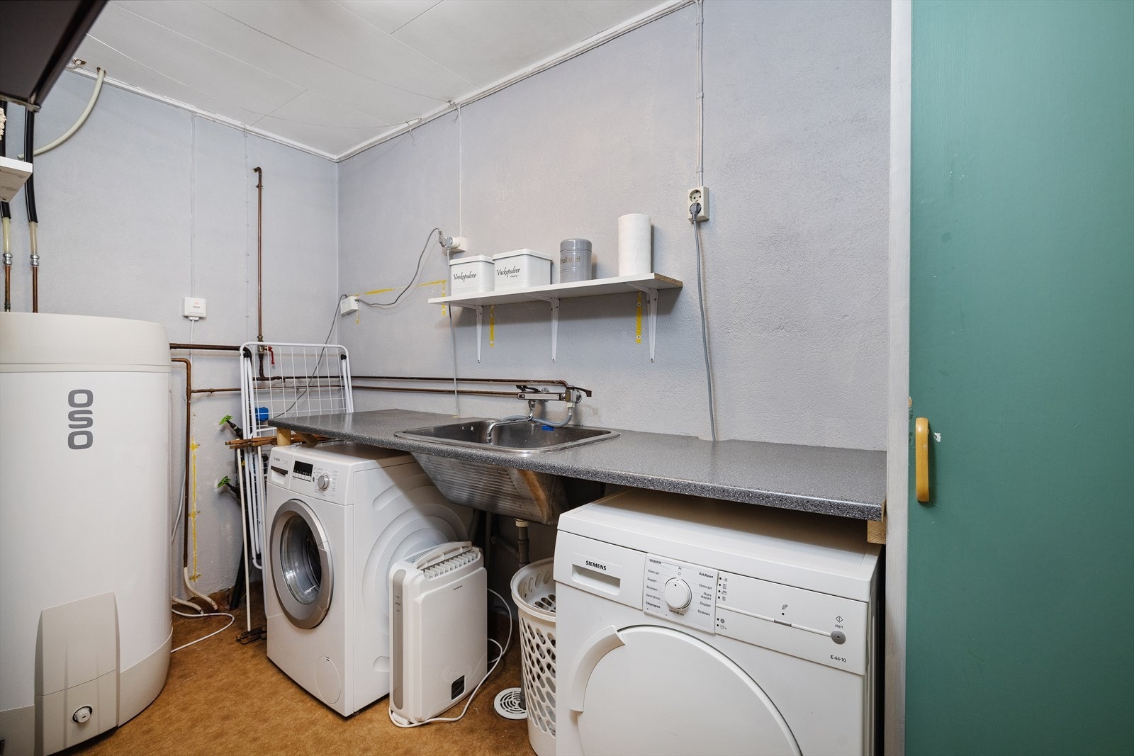 Vaskerommet er fra byggeår, og har opplegg for vaskemaskin og laminert benkeplate med utslagsvask Galleribilde