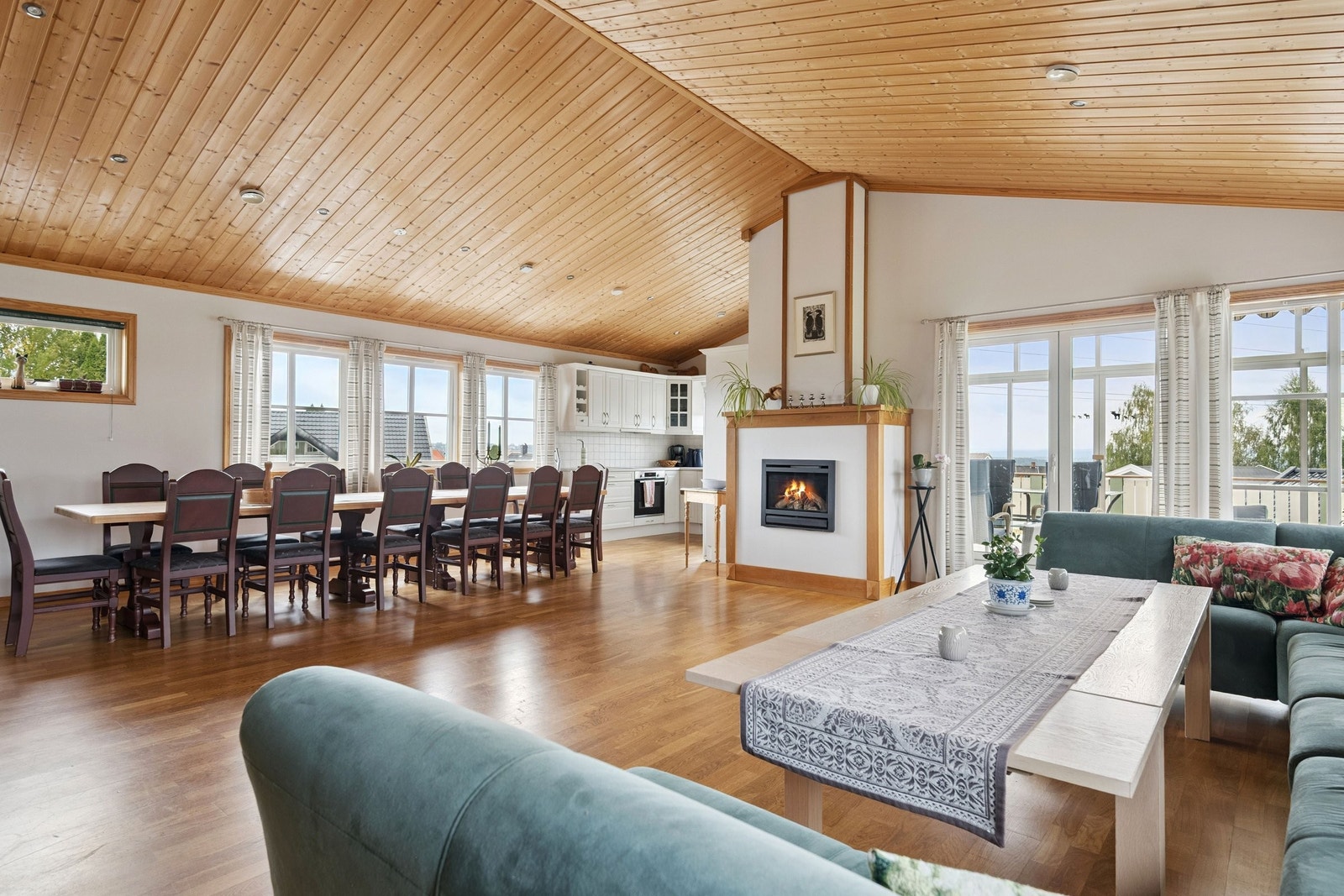 Stor stue i felleshuset med kjøkken, gasspeis og utgang til vinterhage og balkong. Galleribilde