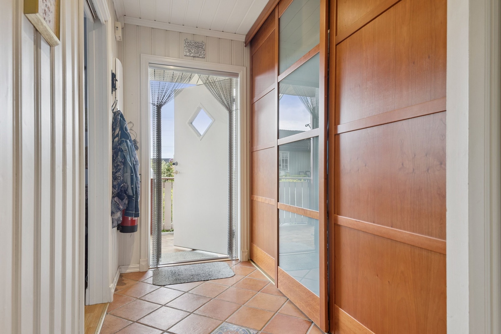 Fliselagt entré med praktisk skyvedørsgarderobe Galleribilde