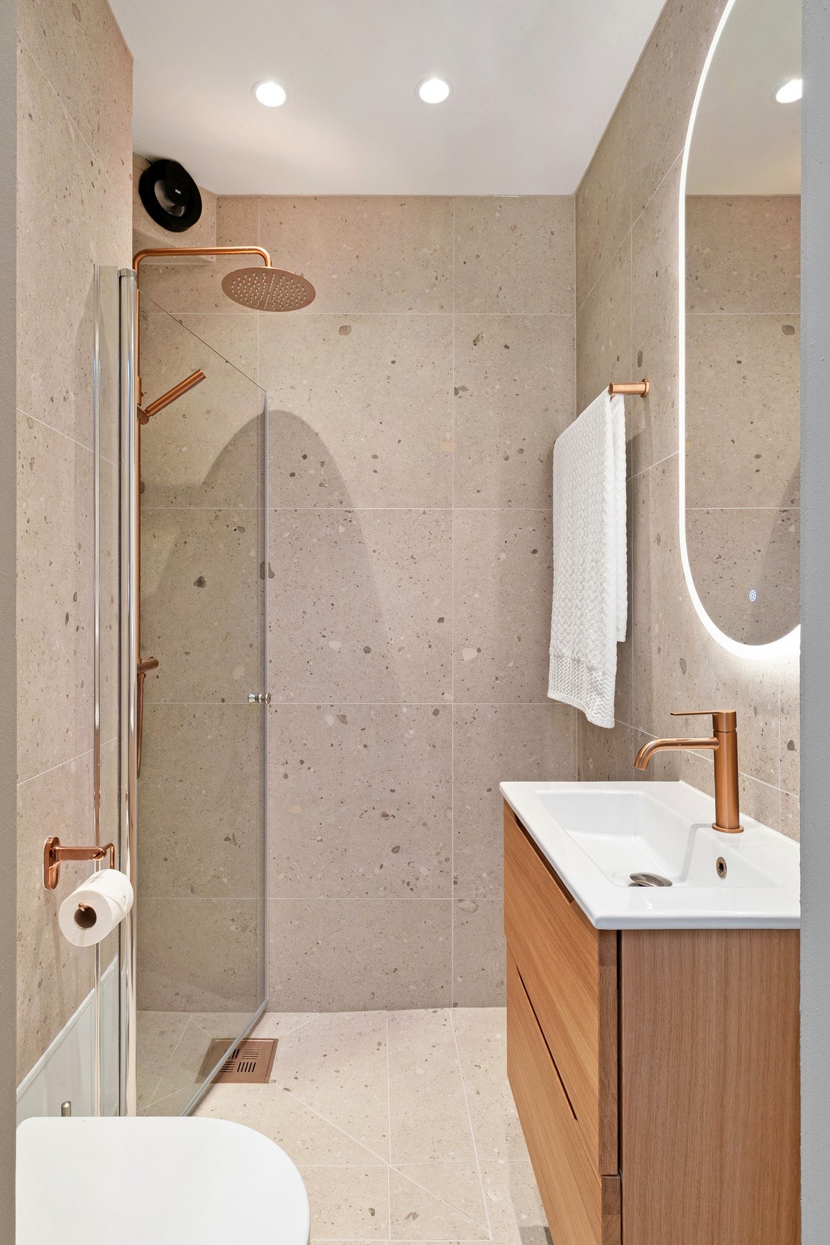 Delikat bad med naturstein-inspirerte fliser i helhetlig utførelse. Galleribilde