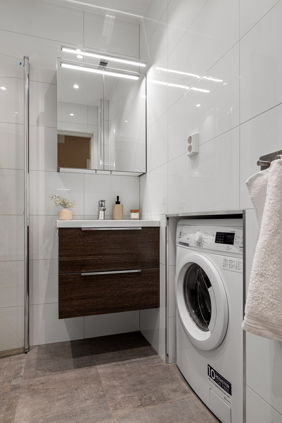 Baderommet har en smart nisje til vaskemaskin og godt med lagringsplass i skuffer- og skap. Galleribilde