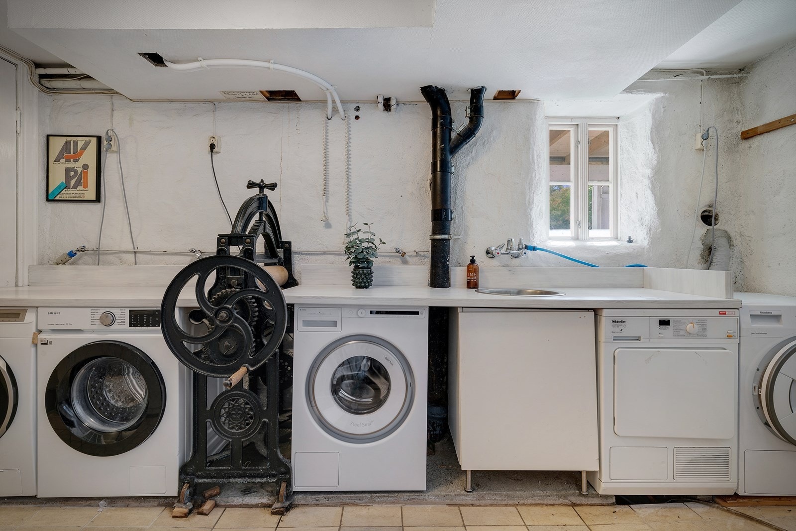 Vaskekjeller med 3 vaskemaskiner og 2 tørketromler. Galleribilde