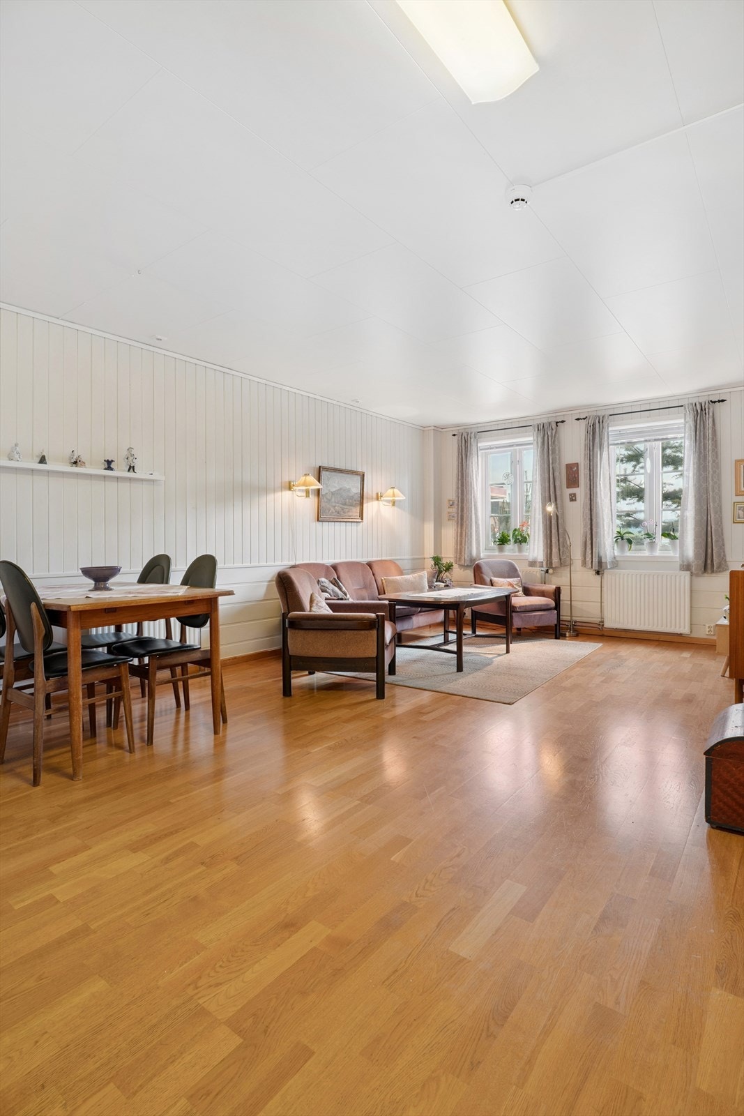 Gjennomgående parkettgulv og vegger med malt trepanel skaper en lun atmosfære. Galleribilde