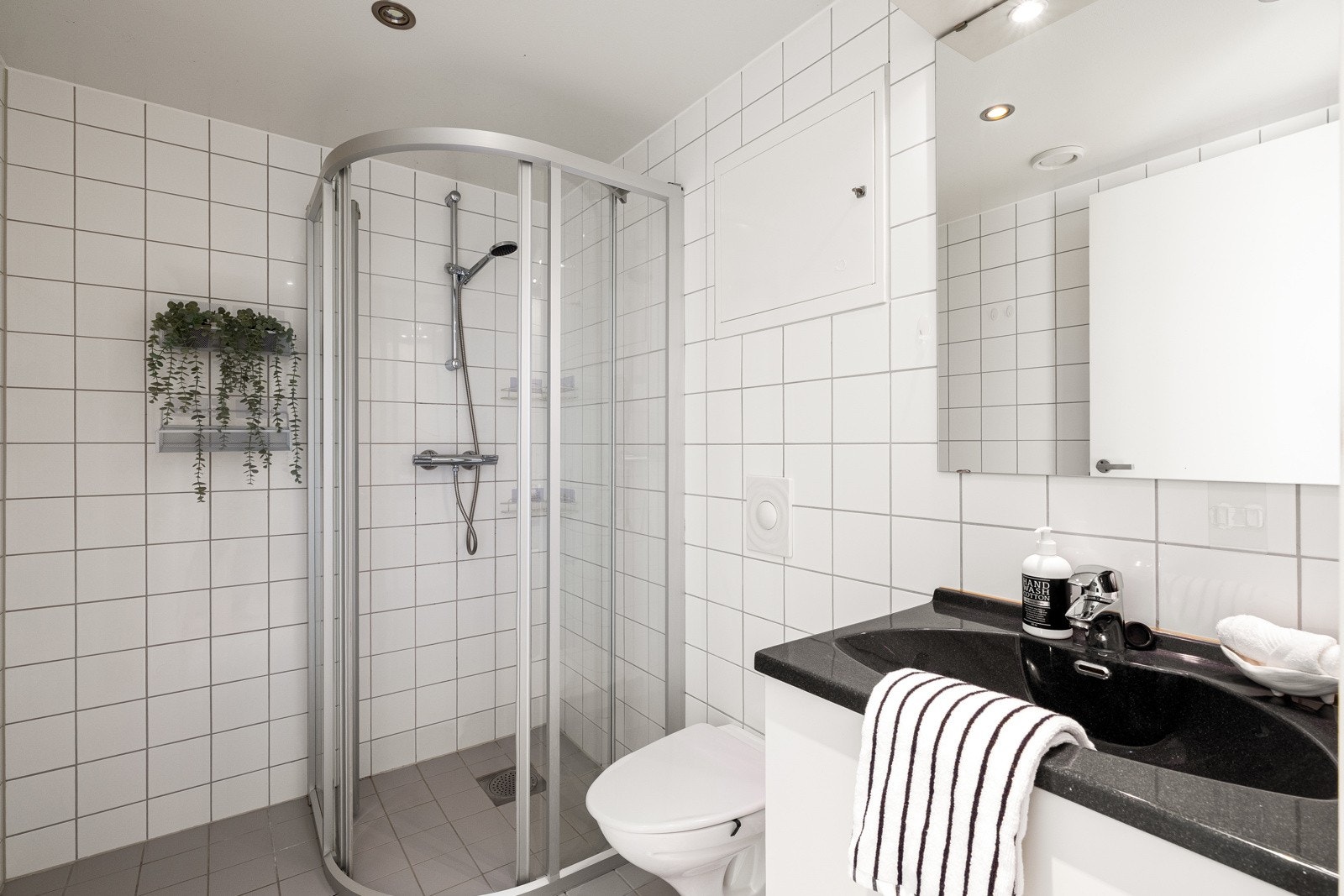 Badet er helfliset og romslig, med dusjhjørne, servant med innredning og vegghengt toalett. Galleribilde
