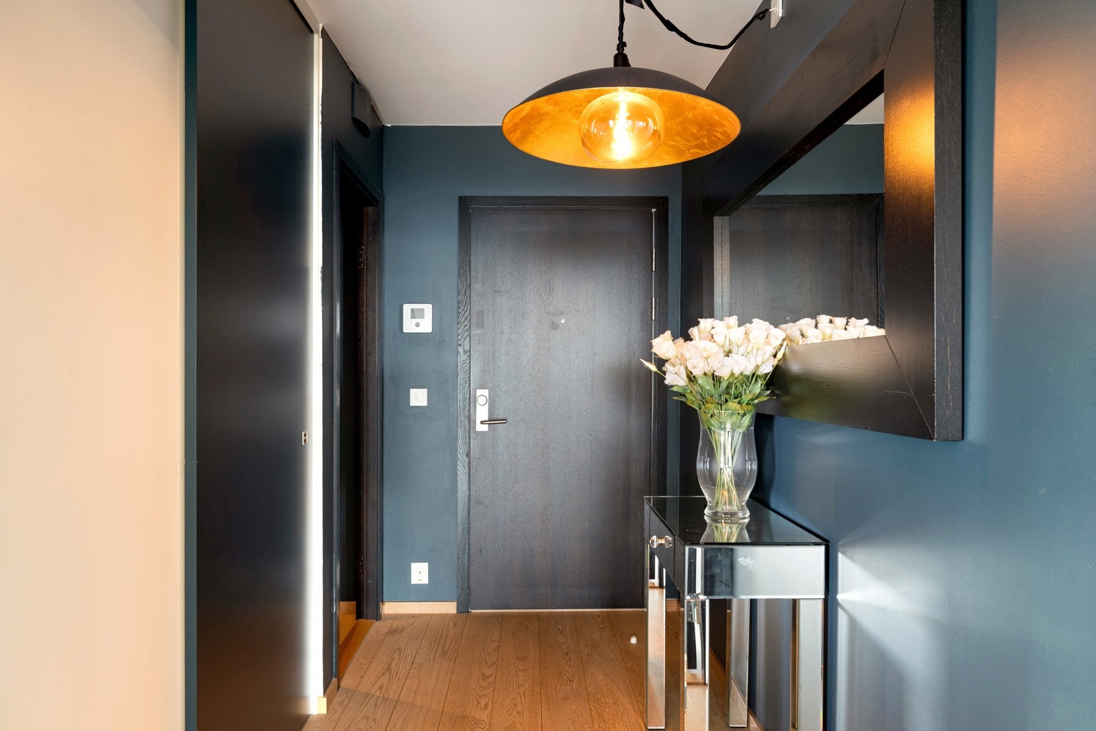 Vel inne i leiligheten møtes man av en innbydende entré. Entréen har god plass for yttertøy og sko i skyvedørsgarderobe, og det er montert dørcalling med bilde-/tale- og lyttefunksjon. Galleribilde