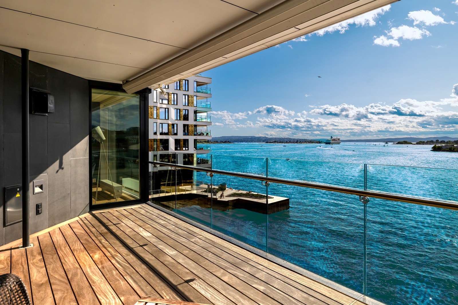 Balkongen har sømløst glassrekkverk, strømuttak og innfelt utebelysning, samt en stor markise som skjermer mot solen Galleribilde