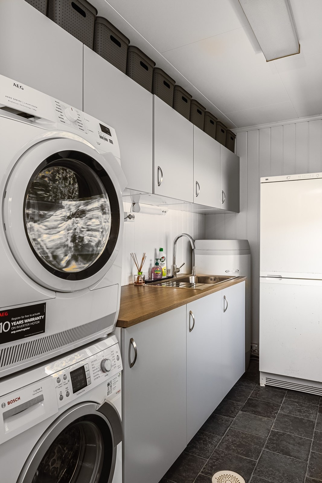 Boligen har et praktisk vaskerom med benker, skap og opplegg for vaskemaskin. Galleribilde