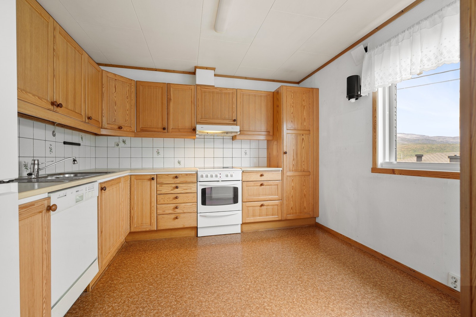 Kjøkkeninnredningen har profilerte fronter i heltre og laminert benkeplate Galleribilde