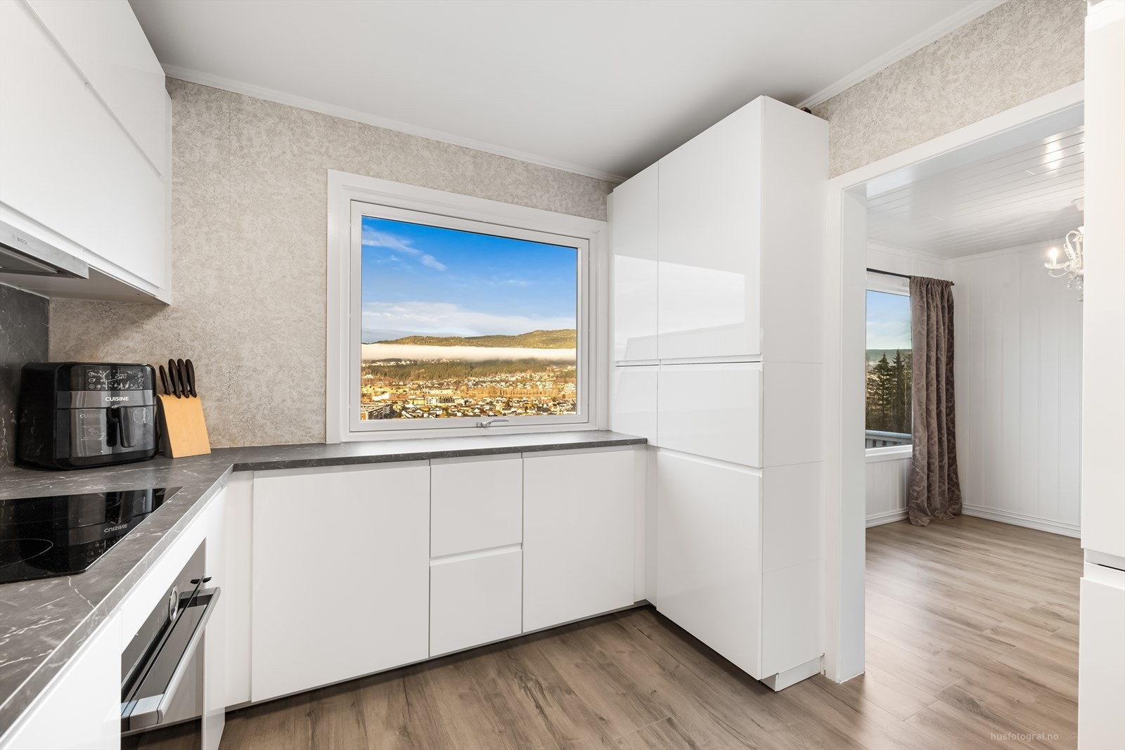 Kjøkkenet har lyse, glatte fronter med innfasede håndtak og slitesterk benkeplate i laminat. Galleribilde