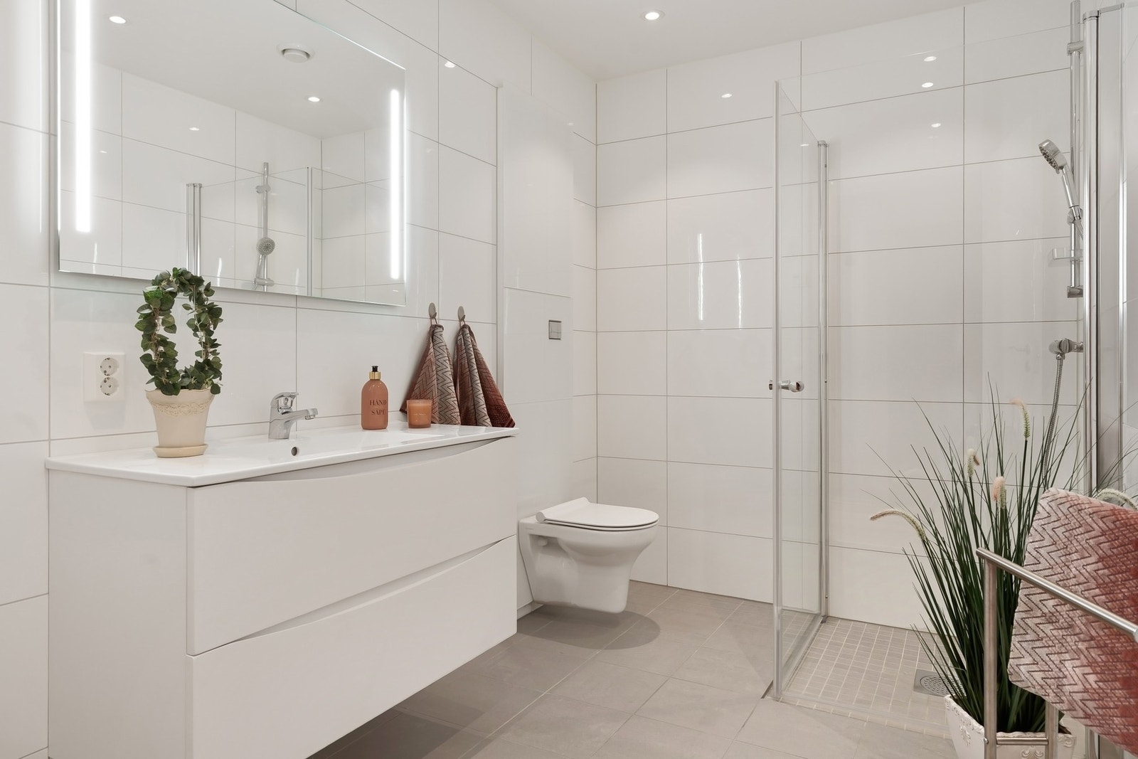 Pent flislagt bad med baderomsinnredning, dusjnisje, vegghengt toalett og gulvvarme. Galleribilde