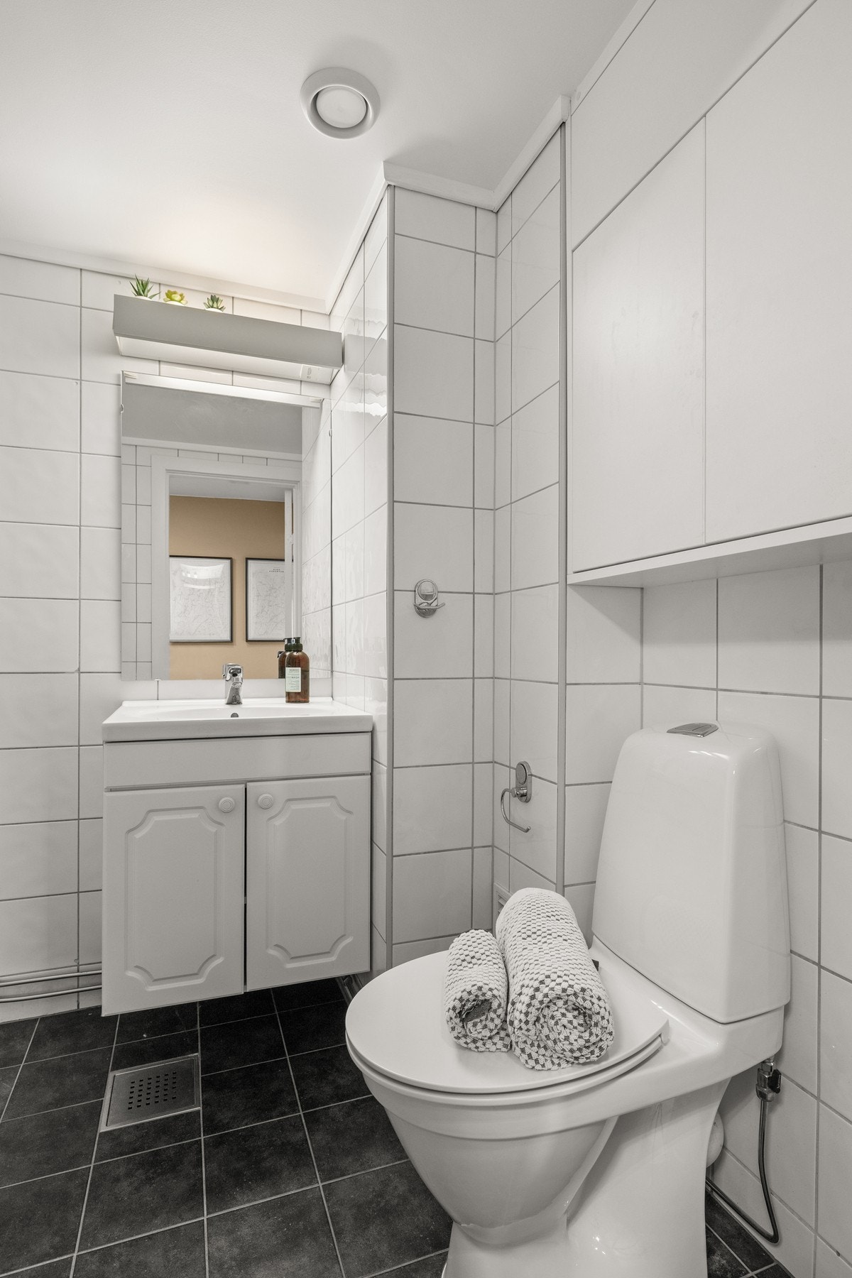 Flislagt bad med gulvvarme. Opplegg for vaskemaskin og tørketrommel. Speil på vegg med overlys og stikkontakt over servant. Galleribilde