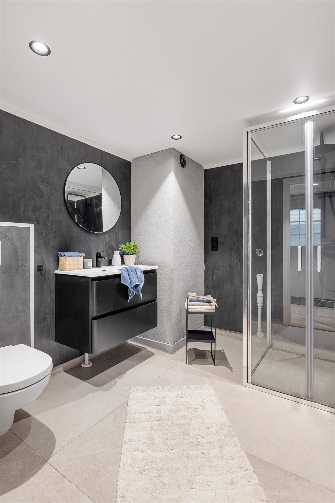 Badet er utstyrt med veggmontert toalett, opplegg for vaskemaskin og baderomsinnredning med skuffer og heldekkende servant. Speil på vegg i overkant. Galleribilde