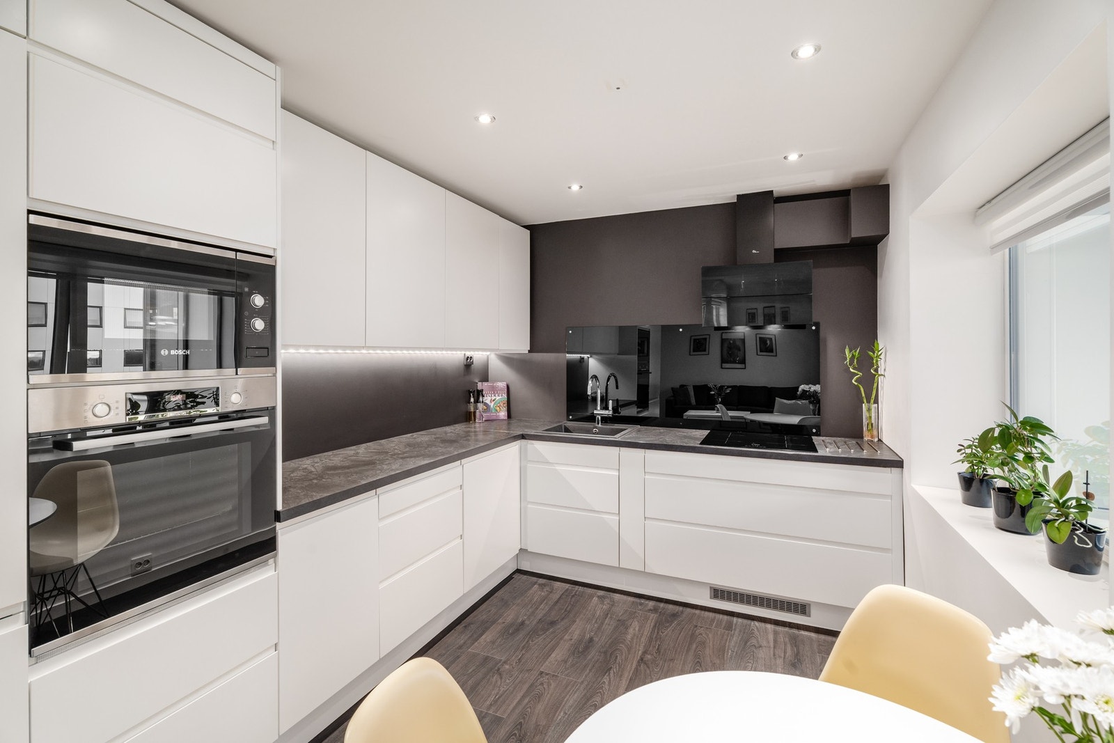 Elegant kjøkken fra 2019 med integrerte hvitevarer, kompositt oppvaskkum og induksjonstopp. Legg merke til elegant glassplate på vegg ved kokesone. Galleribilde