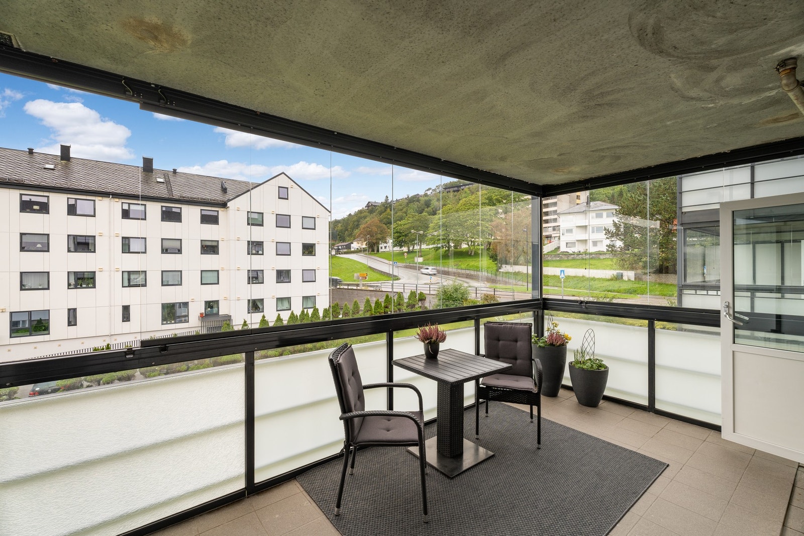 Inneglasset veranda på 12 kvm med flislagt dekke og skyvbar glassfront. Galleribilde