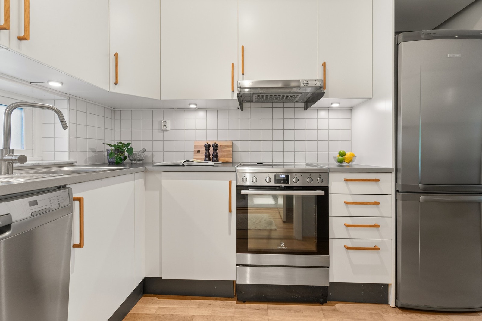 Lyst og pent kjøkken med hvite slette fronter og laminat benkeplate. Galleribilde