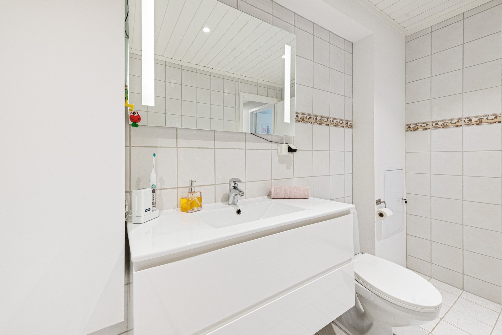 Badet fremstår som et innbydende og praktisk rom med god plass til oppbevaring av baderomsartikler og tekstiler. Et funksjonelt rom der design og komfort møtes i hverdagen. Galleribilde