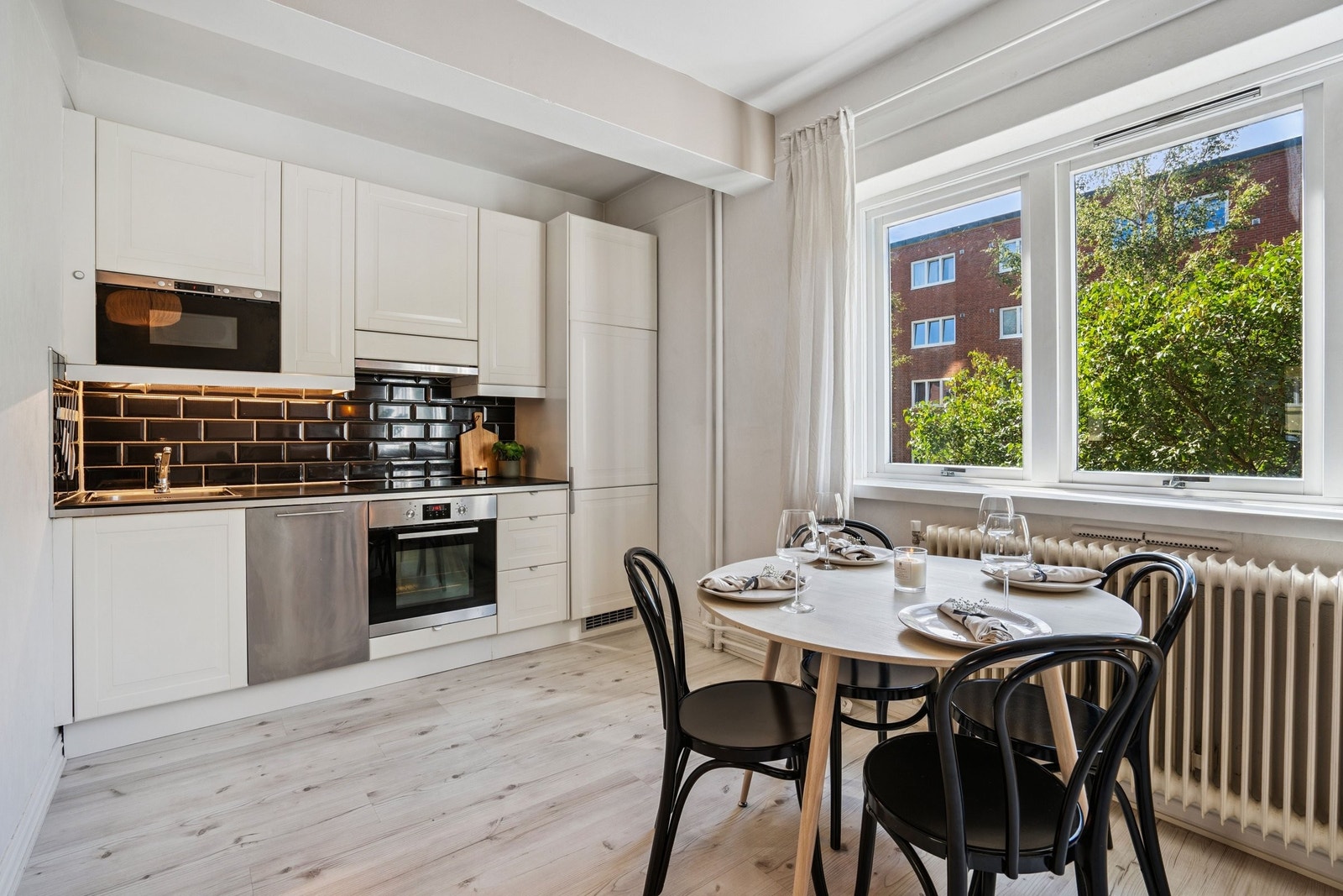 Lyst kjøkken med spiseplass og utsikt mot grøntarealer Galleribilde