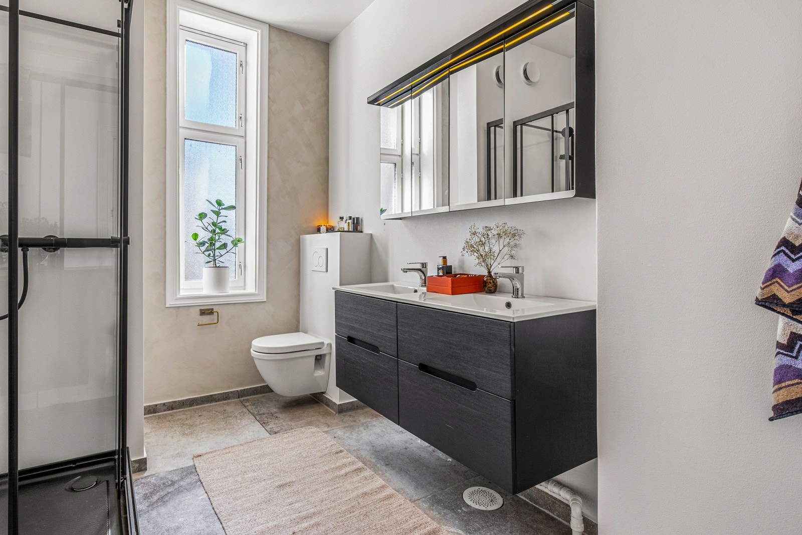 Badet inneholder dobbelservant med underskap, speil, vegghengt toalett og dusjkabinett (2024). Galleribilde