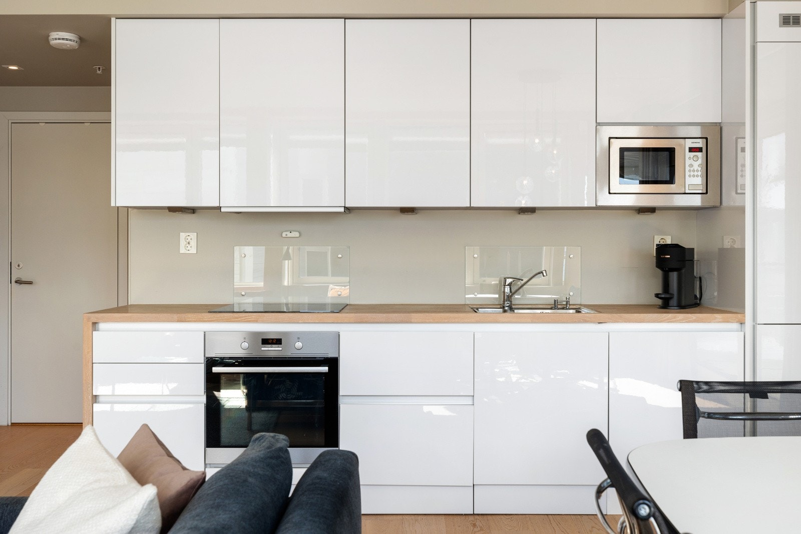 Sprutsonene er beskyttet med stilrene glassplater, og belysningen under overskapene gir godt arbeidslys og fremhever de rene linjene. Galleribilde