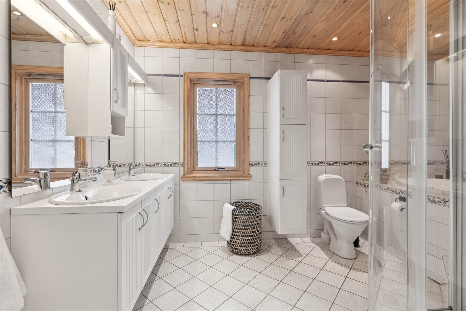 Boligens første baderom er lokalisert i 1. etasje. Rommet er gjennomført med lyse fliser på gulv og vegger, med flotte og tidløse fargetoner. Galleribilde