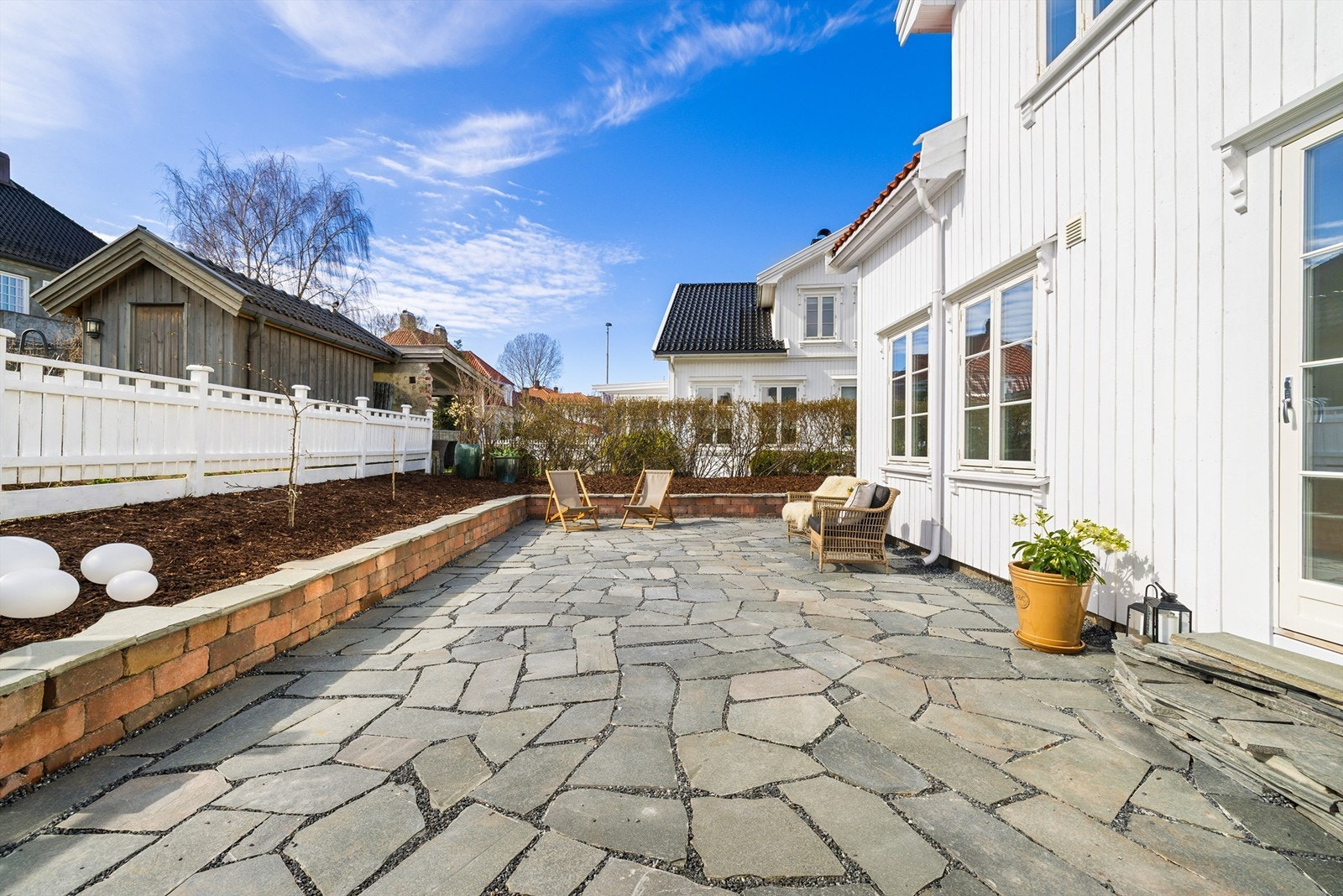 Rundt uteplassen er det beplantet og barket mot forstøtningsmur av teglstein og skiferheller. Galleribilde