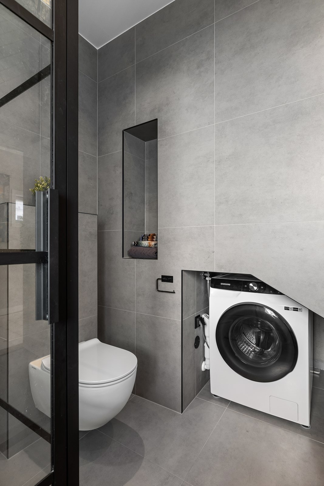 Vaskemaskinens plass er inntrukket og lite fremtredende, men likevel lett tilgjengelig i nisje som utnytter volumet under trappen. Galleribilde