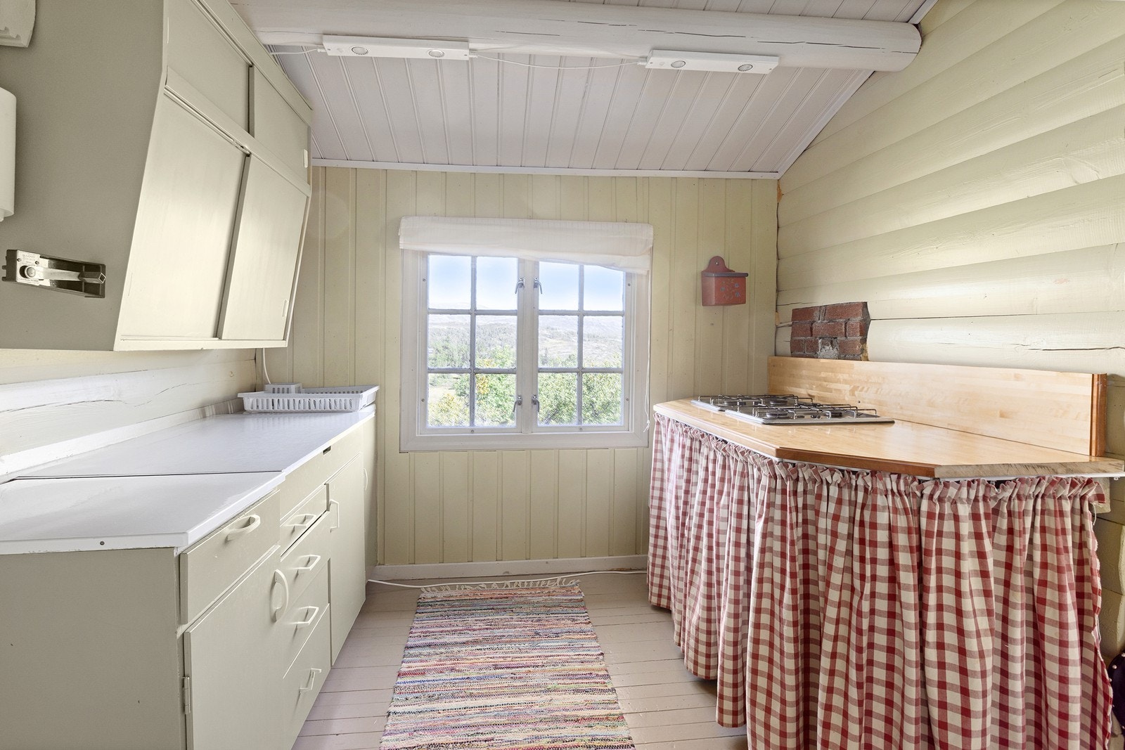 Enkel kjøkkeninnredning med diverse skap- og benkeplass. Gasstopp på høyre side. Galleribilde