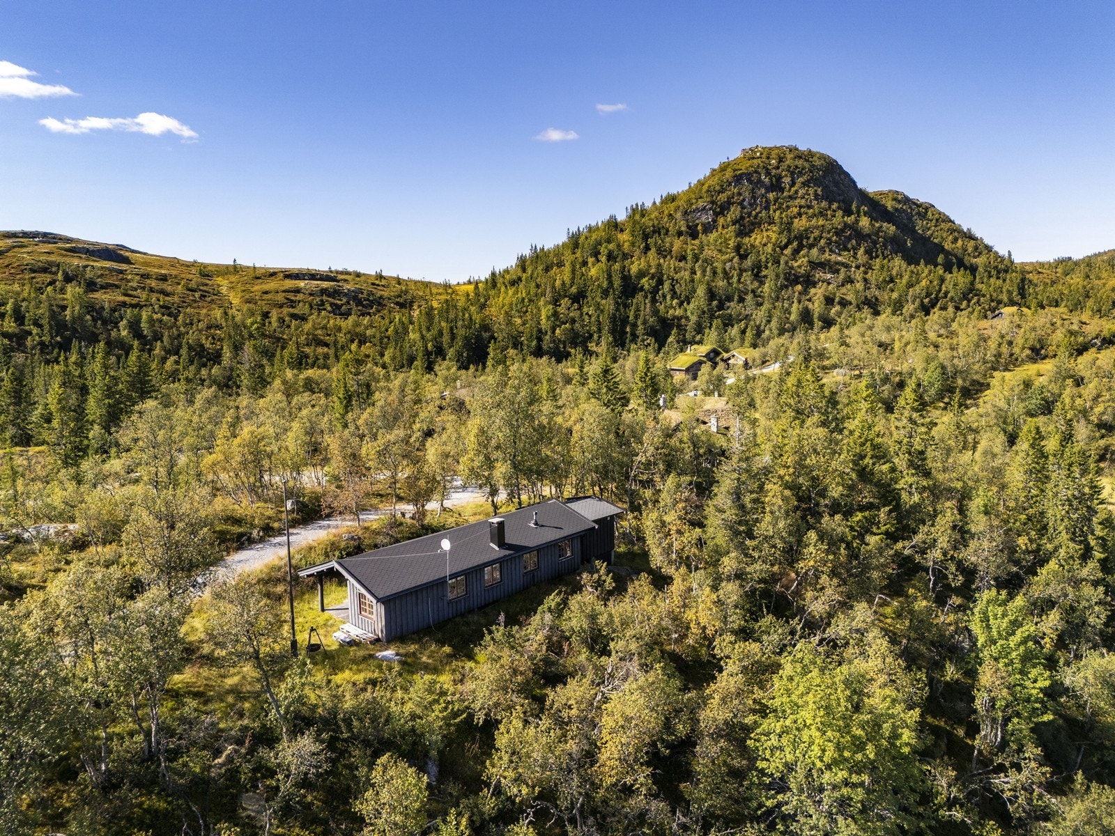 Tomten er i all hovedsak en naturtomt med gruset parkeringsplass skrått ovenfor hytta. Galleribilde