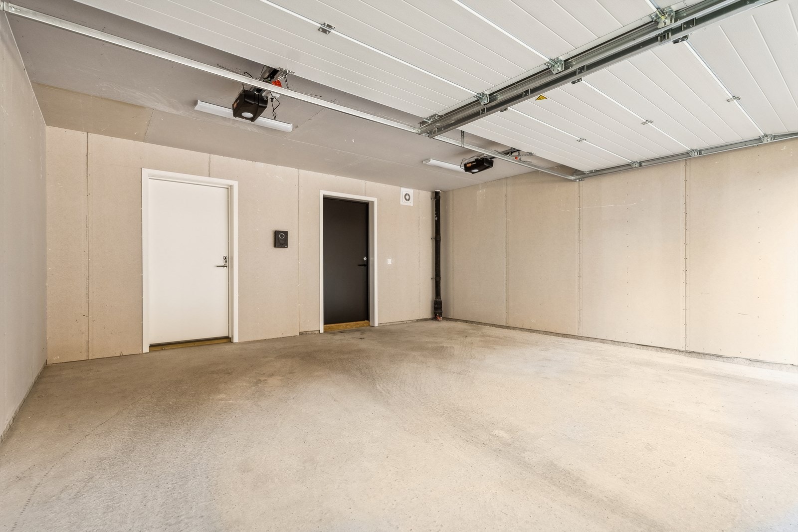 Romslig garasje med plass til to biler. Det er innsatt egen EL-bil lader. Garasjen har egen innebygd sportsbod og utgang til boligens gressplen. Galleribilde