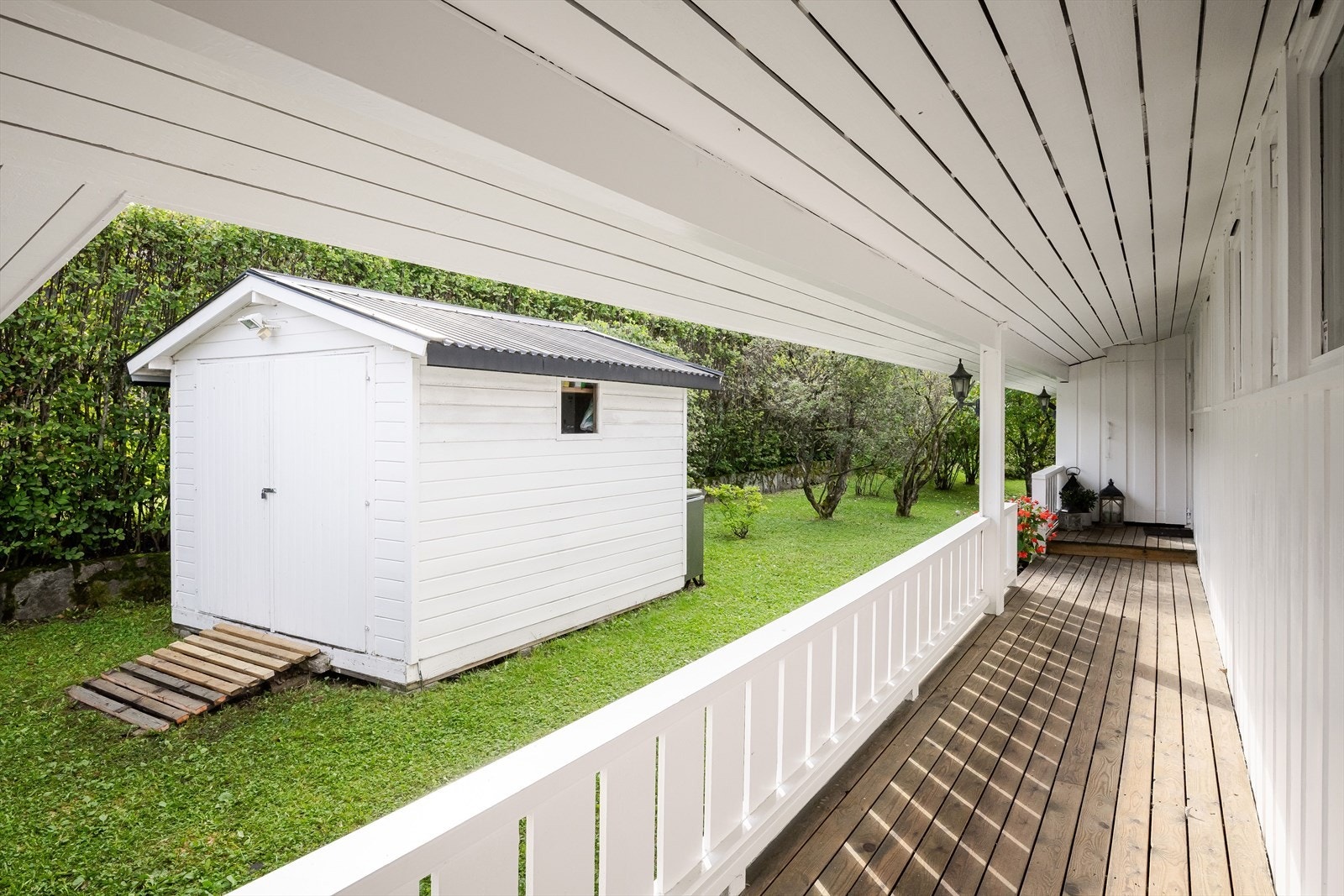 Du ønskes velkommen inn via en overbygget svalgang med terrassebord og lysmalt rekkverk. Eiendommen er også bebygd med en praktisk redskapsbod på ca. 7m². Galleribilde