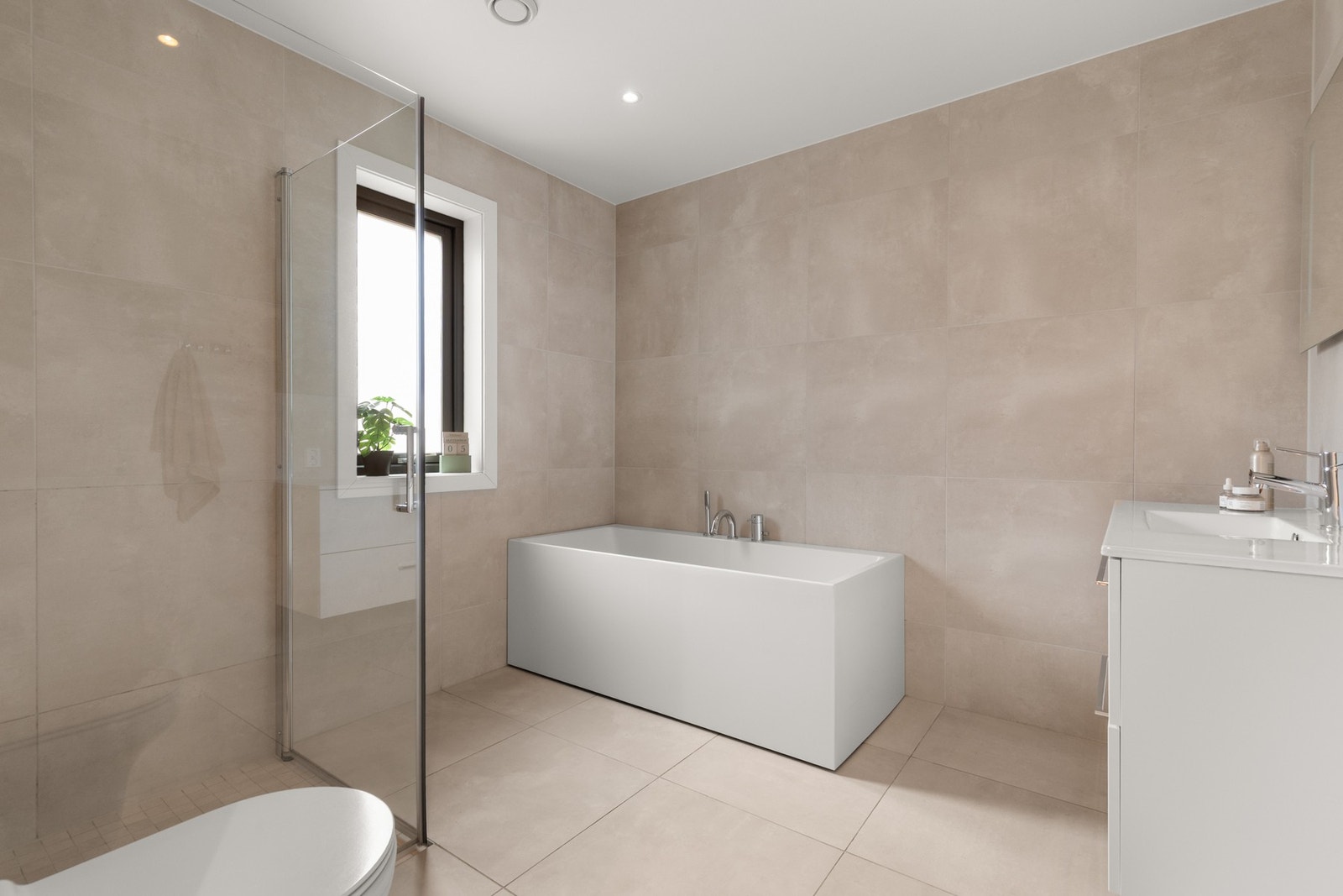 Hovedbadet er moderne innredet med både badekar og dusj, servantseksjon med skuffer, speil med belysning samt vegghengt toalett. Galleribilde