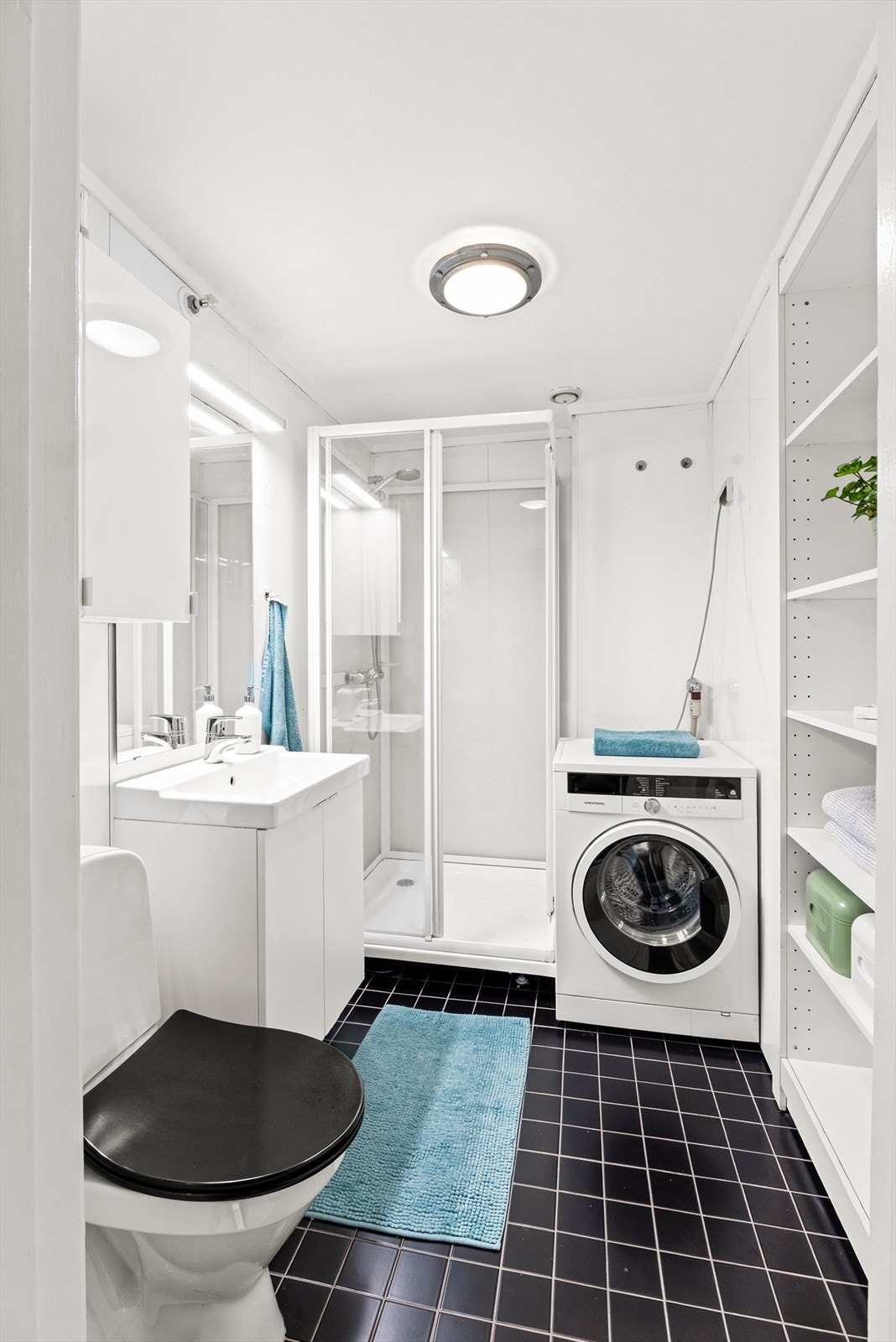 Badet har flislagt gulv og baderomsplater på vegger, og er av eldre dato. Det er utstyrt med dusjkabinett, servant i helstøpt plate, gulvstående toalett og opplegg for vaskemaskin. Galleribilde