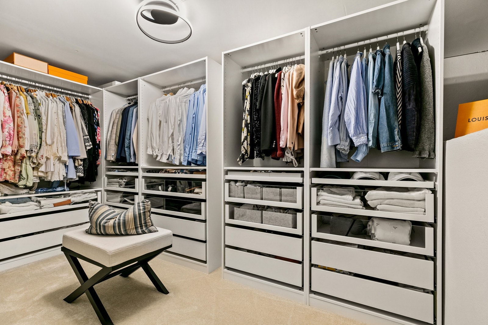 Walk in closet er praktisk innredet med en oversiktlig hylleinnredning med klesoppheng, åpne hyller og skuffeseksjoner Galleribilde