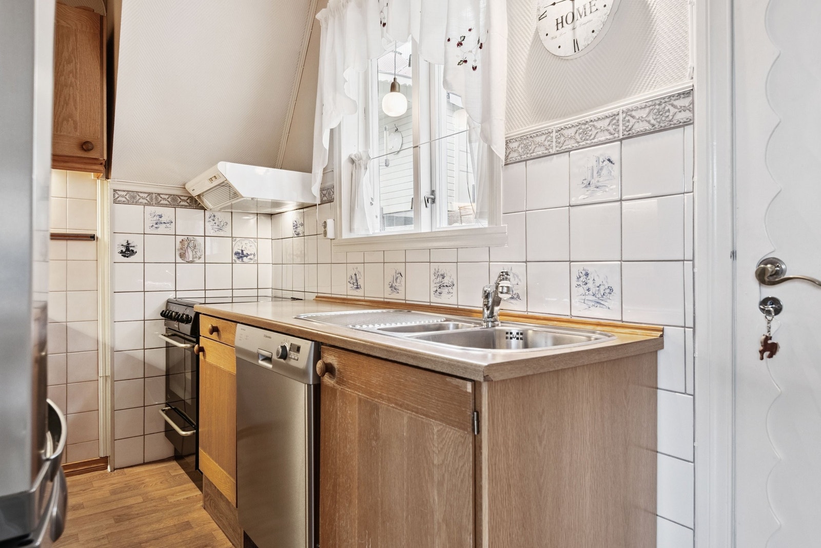 Kjøkken med komfyr, kjøleskap og oppvaskmaskin, samt veggmontert ventilator. Galleribilde