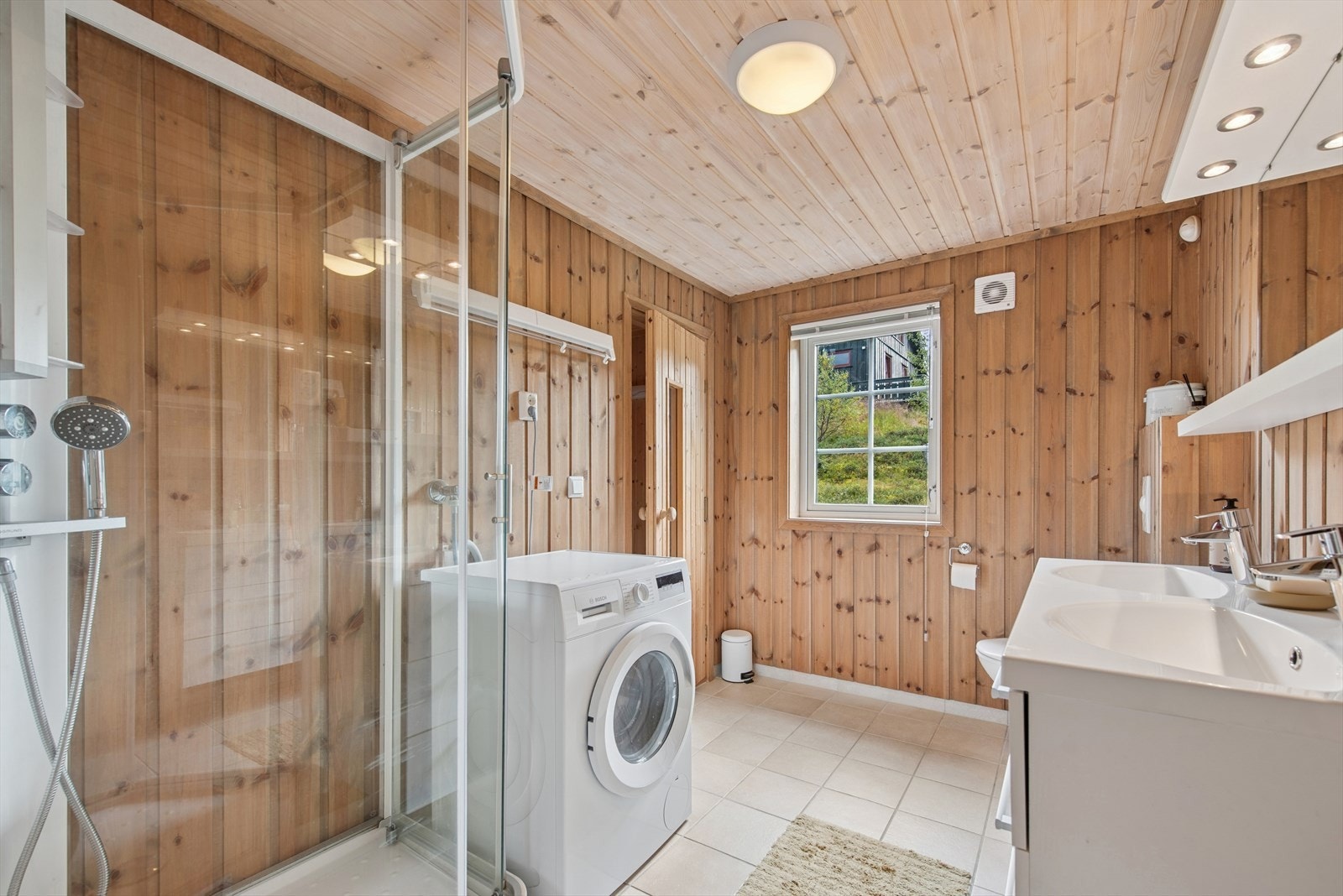 Badet er romslig og velutstyrt med dusjkabinett, dobbel servant, vegghengt toalett og opplegg for vaskemaskin. Galleribilde