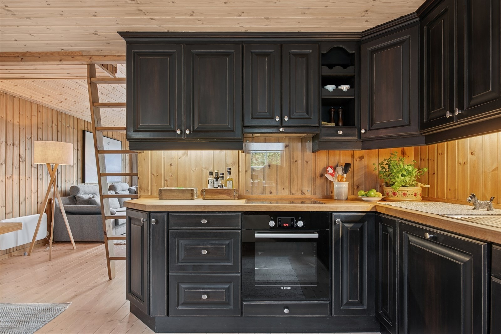 Integrerte hvitevarer og et takhøyt vitrineskap mellom vinduene gir både funksjonalitet og eleganse, og harmonerer vakkert med tregulvet og panelveggene. Galleribilde