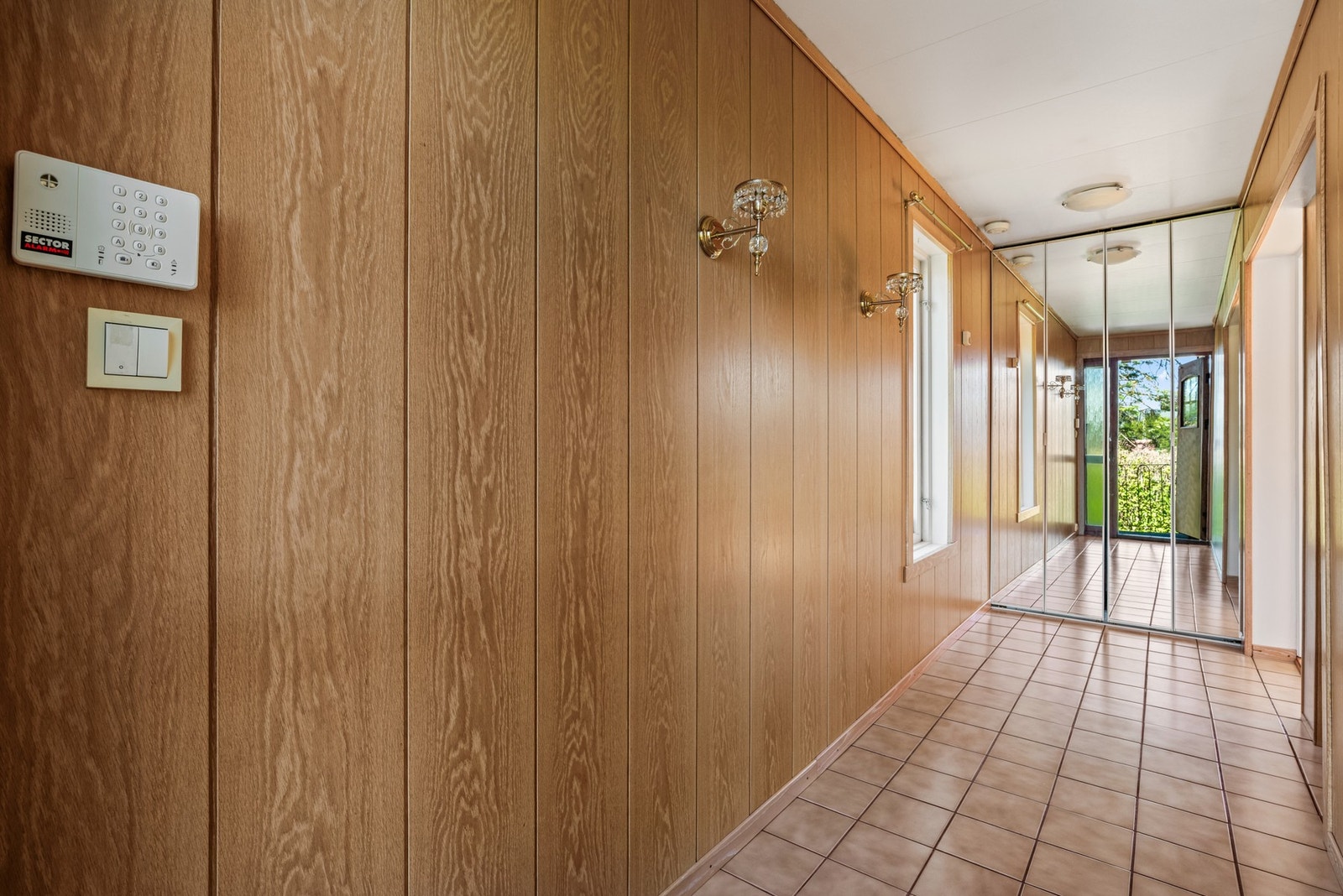 Romslig entré/gang med fliser på gulv og garderobeskap med speilfronter Galleribilde