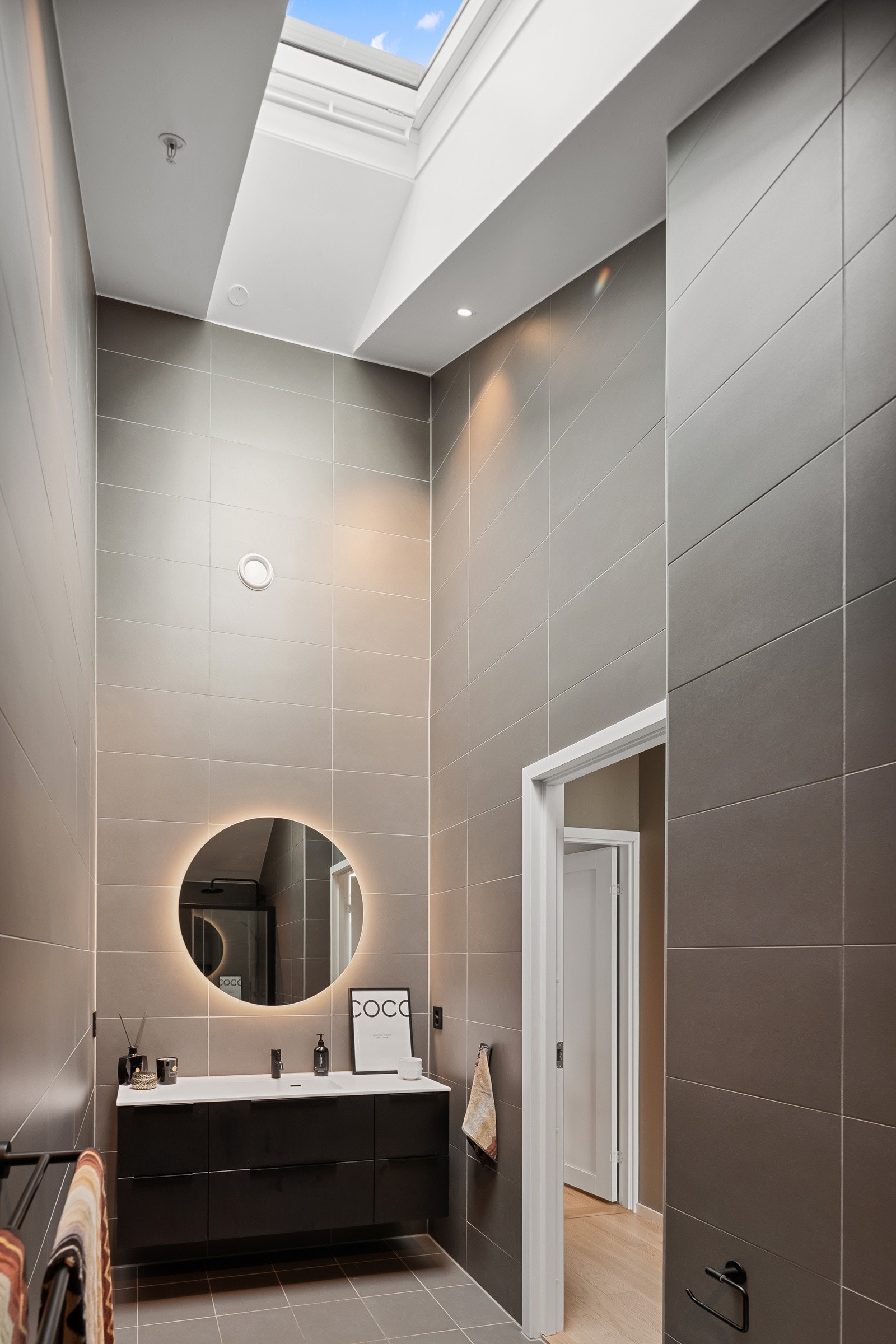 Baderommet har glatte malte himlingsflater med elegante downlights og flott takvindu Galleribilde