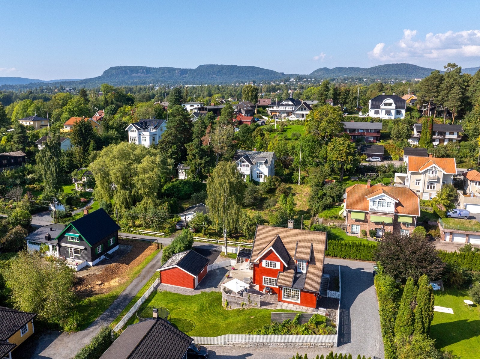 Solrik tomt, innrammet med hvitt stakittgjerde. Galleribilde