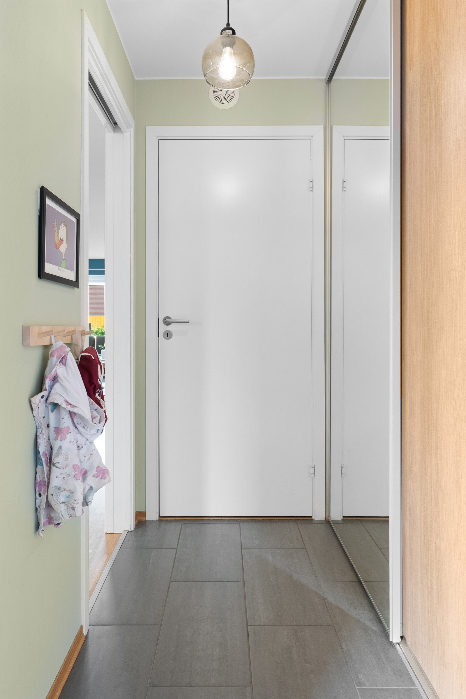 Entréen har en romslig utforming og byr på både komfort og funksjon med behagelig gulvvarme og gode oppbevaringsmuligheter i skyvedørsgarderobe. Galleribilde