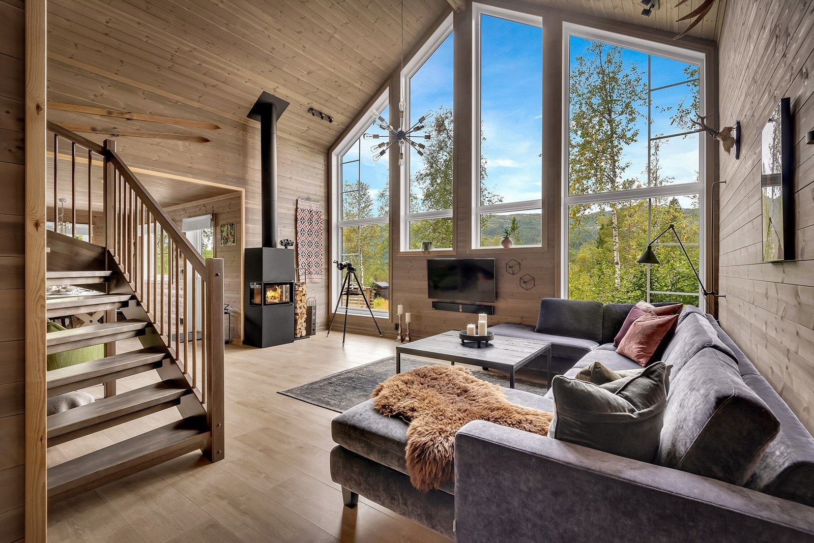 Romslig stue med god takhøyde og store flotte vinduer som slipper rikelig inn med lys i rommet. Stuen er innredet med sofagruppe med puff, stuebord og TV-møblement. Galleribilde