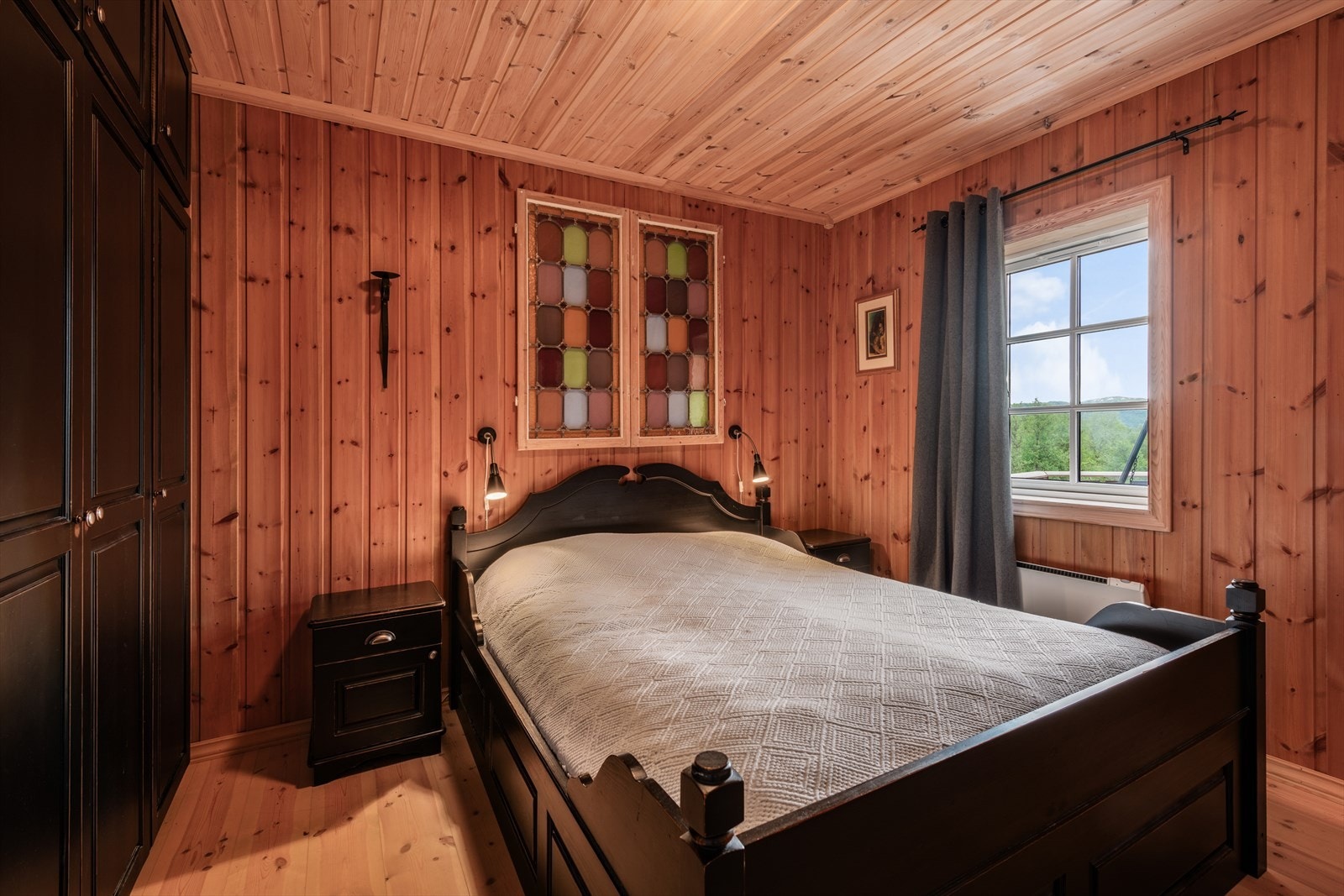 Koselig soverom med tregulv og panelvegger. Stort vindu slipper inn naturlig lys og gir en flott utsikt. Galleribilde