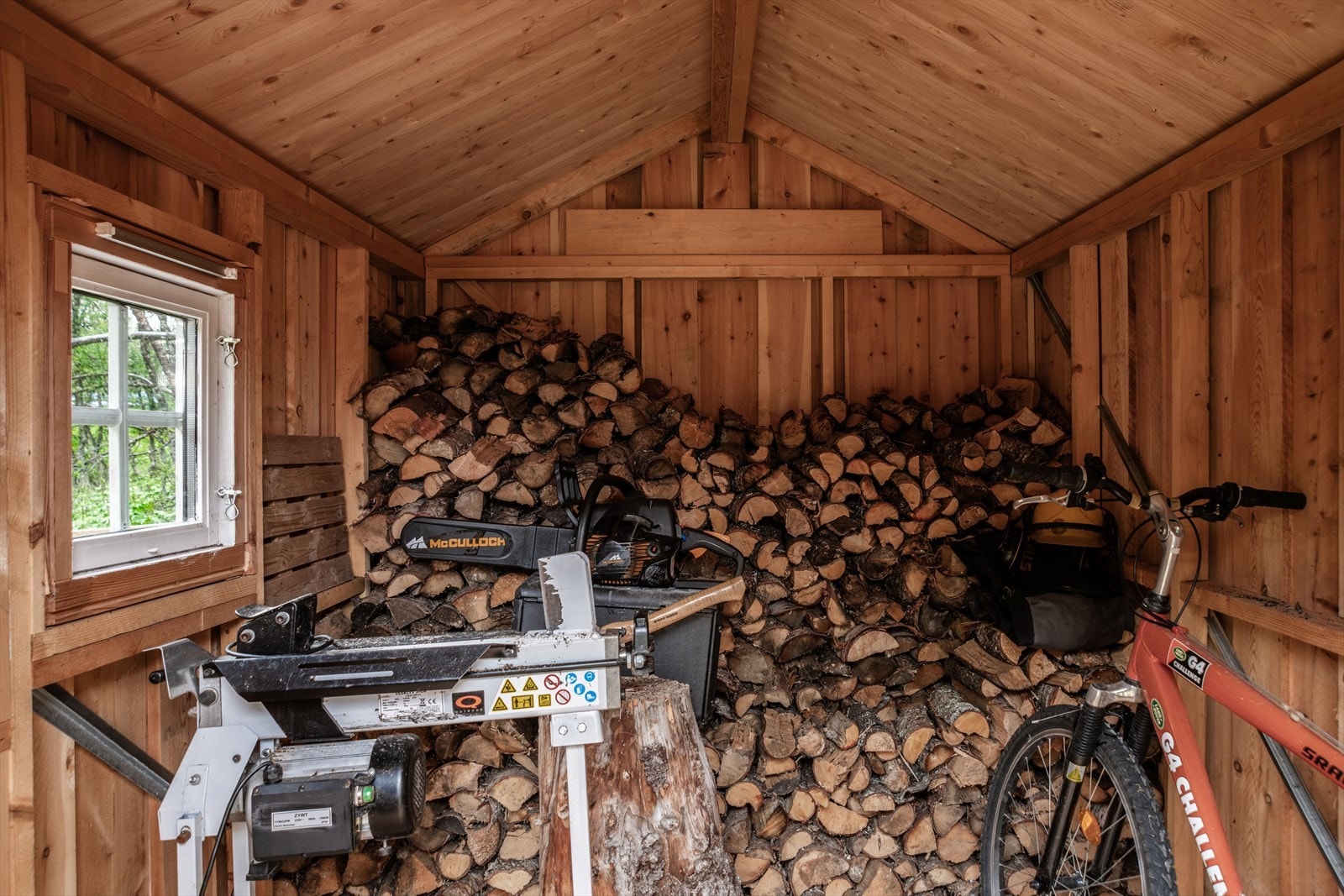 Romslig uthus med god plass til oppbevaring av ved og utstyr. Galleribilde