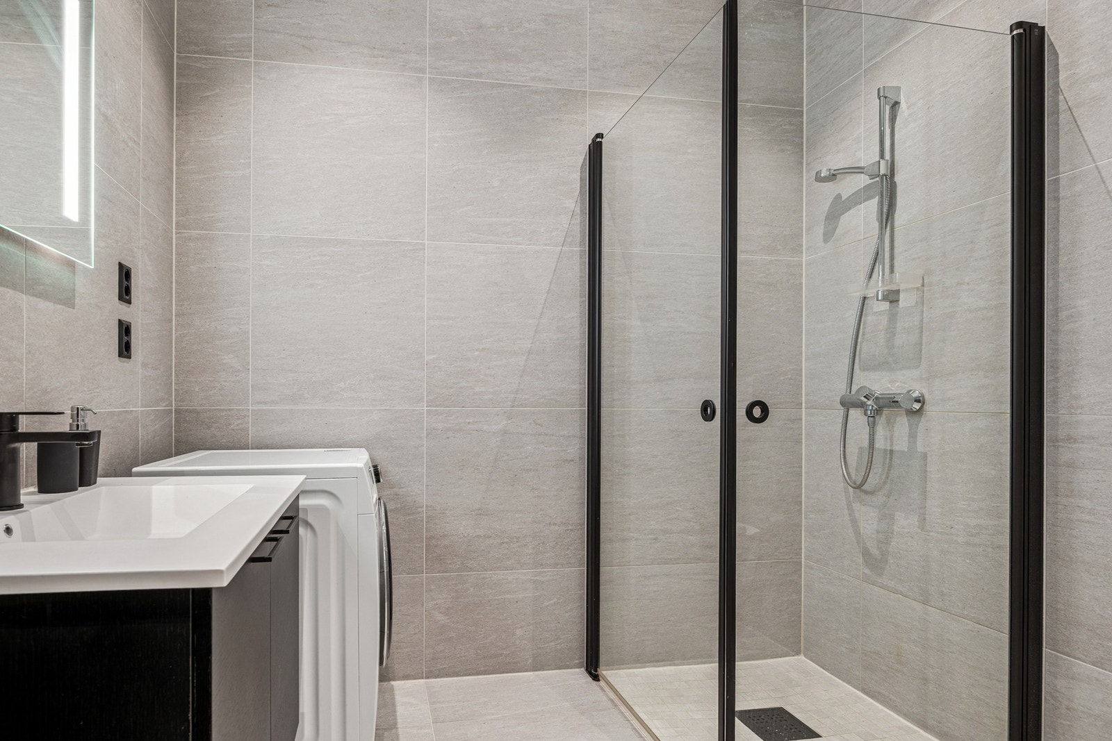 Badet er utstyrt med servantinnredning, speil med lys, vegghengt toalett og dusjhjørne med innfellbare dusjdører, samt opplegg for vaskemaskin. Galleribilde